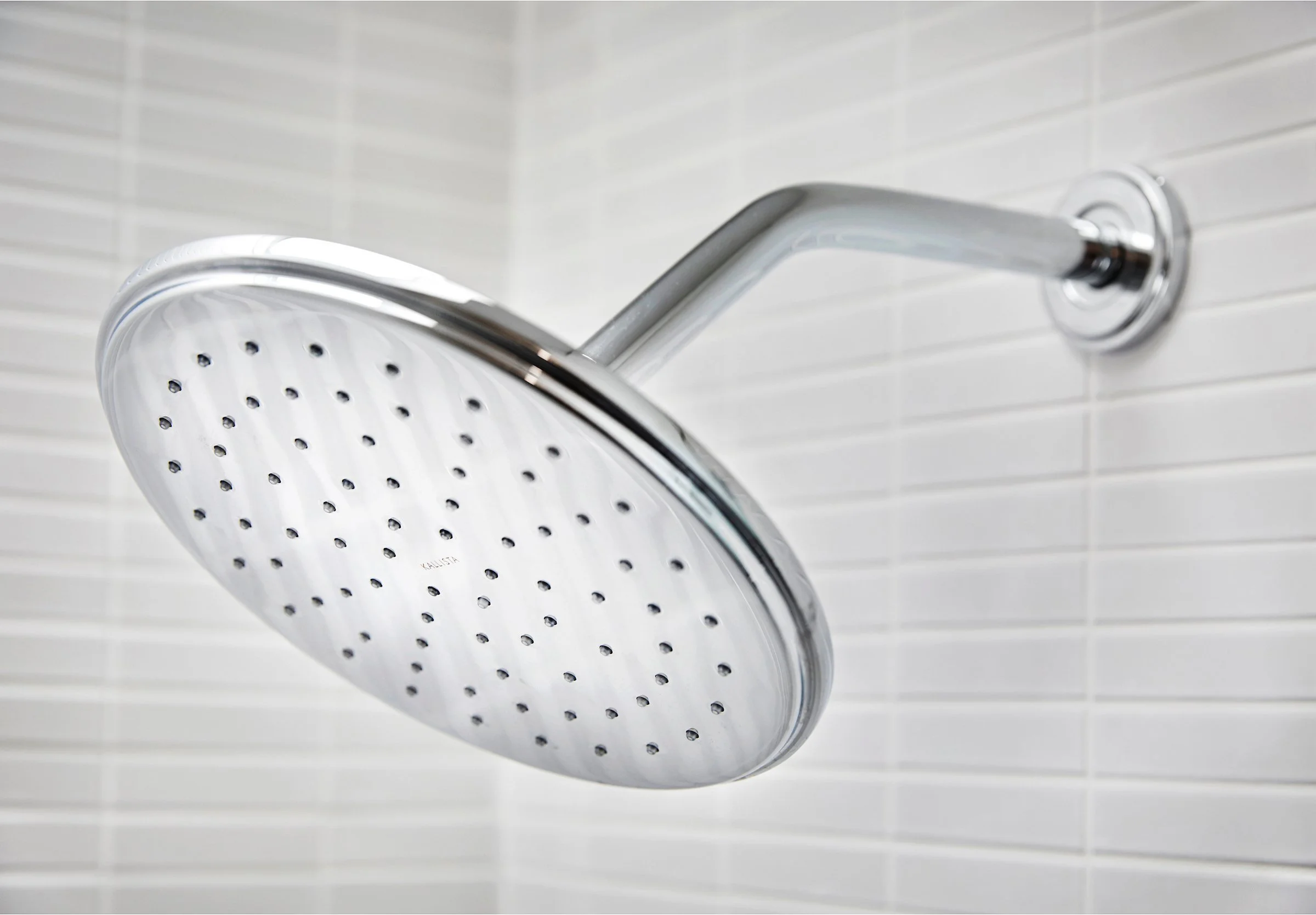 A chrome showerhead mounted on a tiled wall.