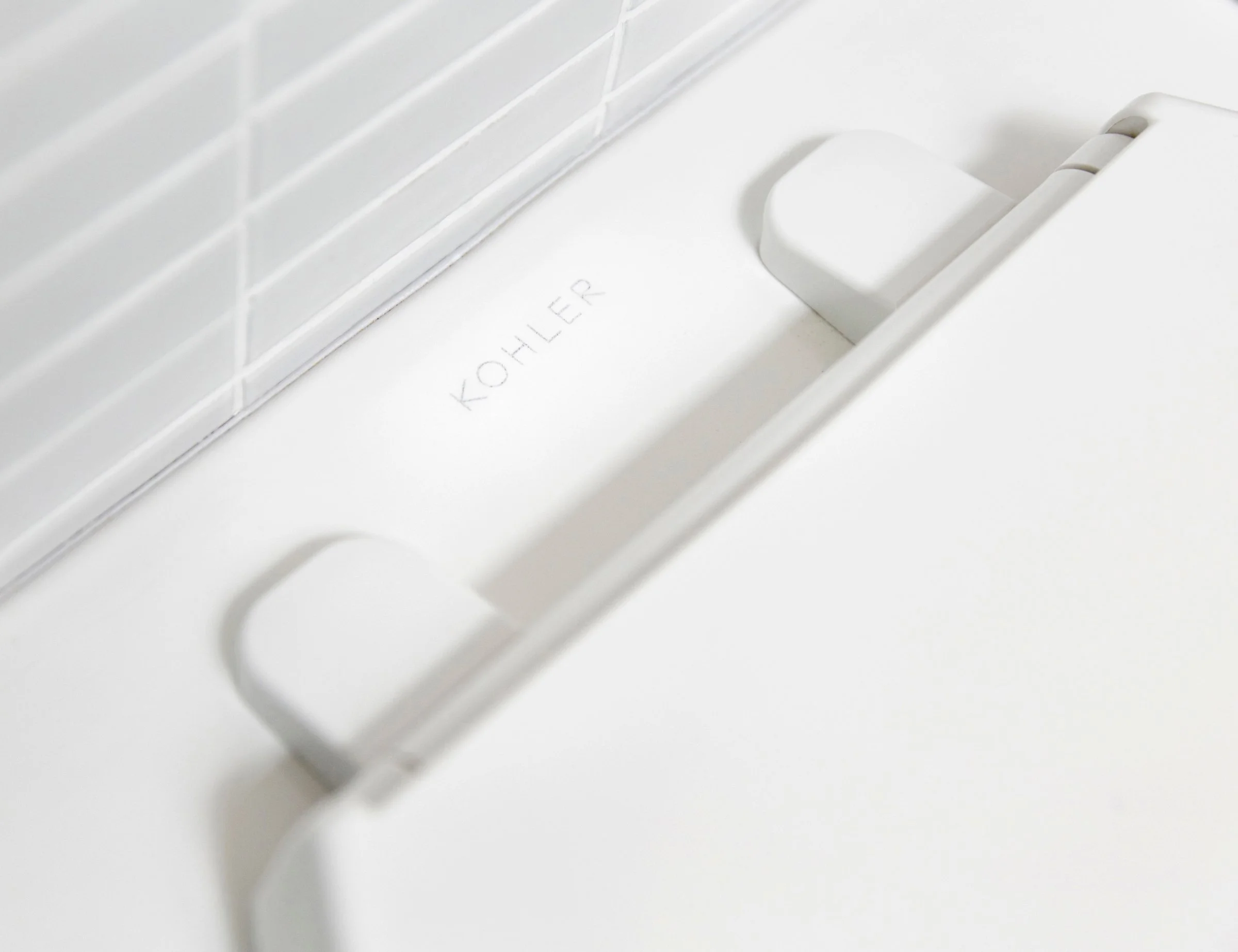 Close-up of a white Kohler dishwasher with the brand name visible on the interior door.