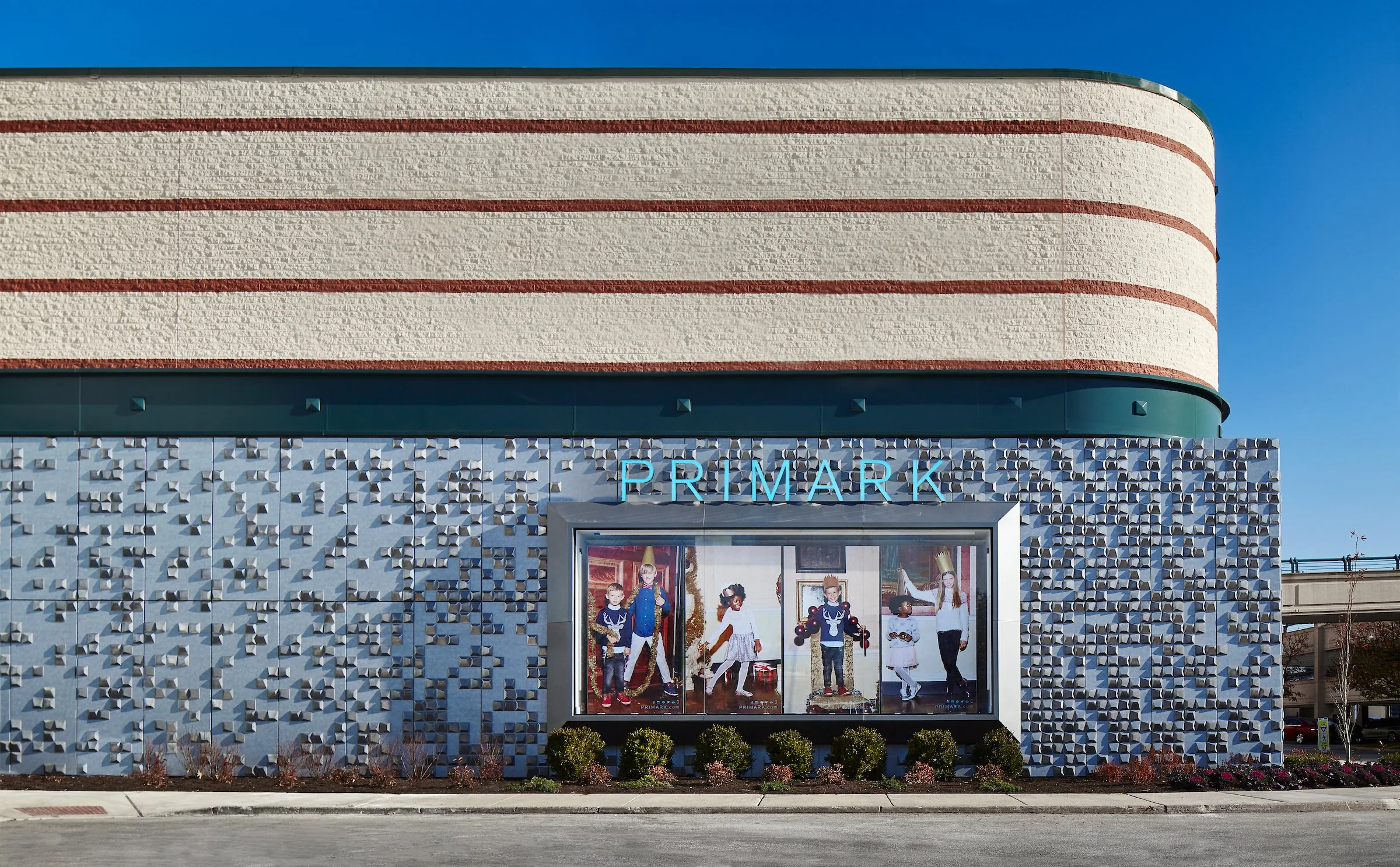 Exterior of a Primark store with a window display featuring children in festive clothing, with the store name in blue above.
