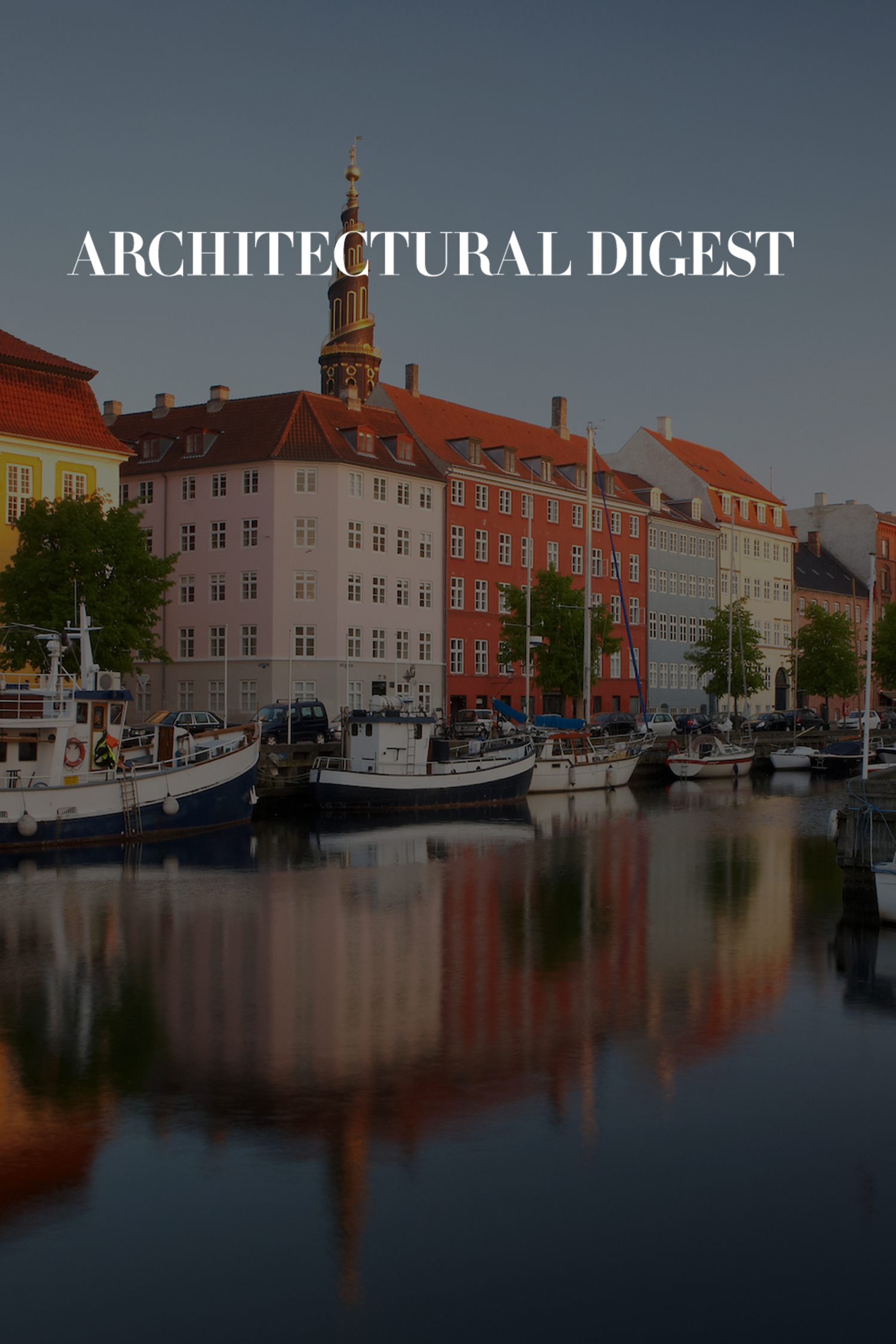 Cover photo of Architectural Digest magazine featuring a waterfront scene with colorful buildings, boats, and a church steeple reflected in the water.