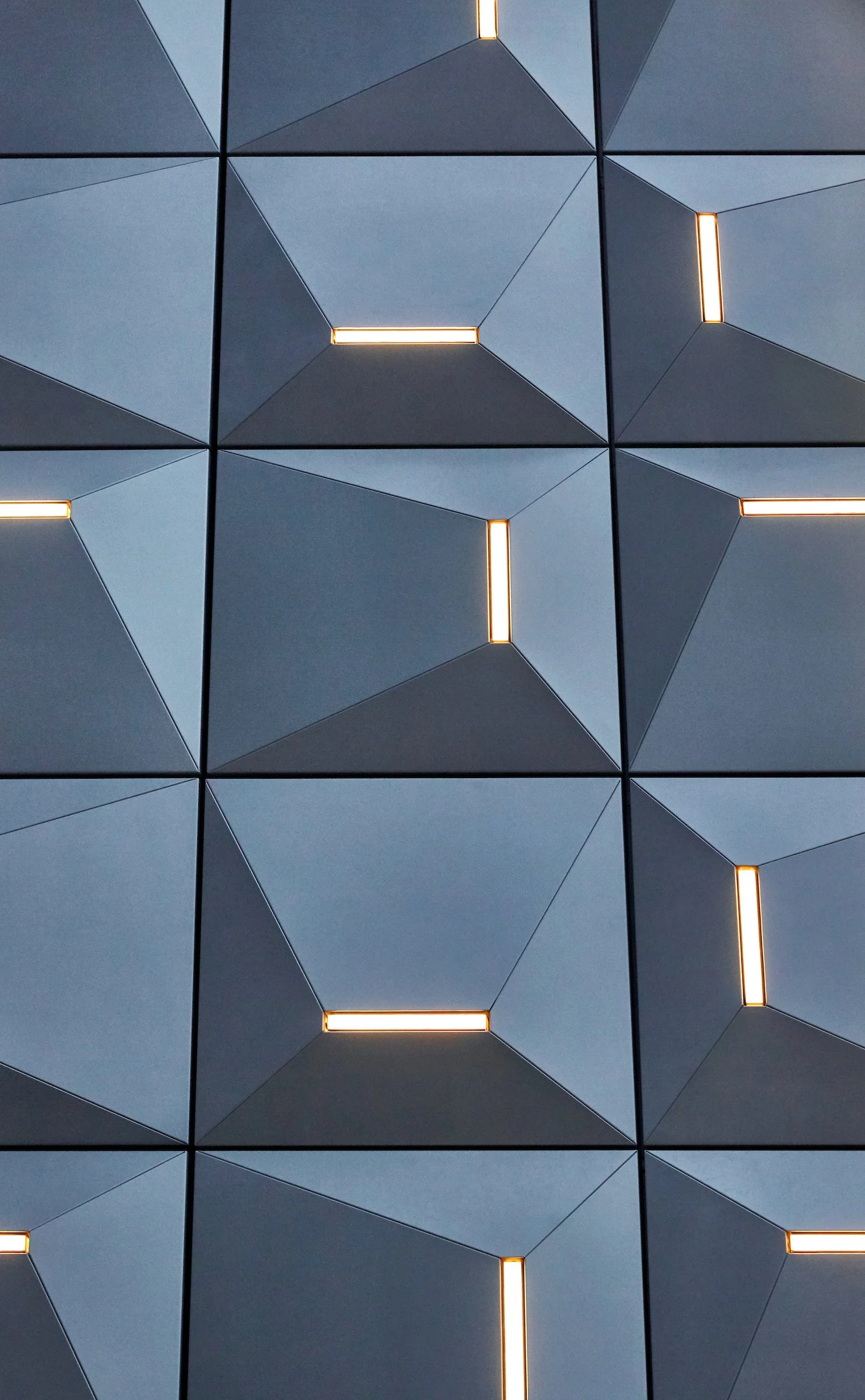 Close-up of a modern building facade with geometric tile patterns and built-in strip lighting.