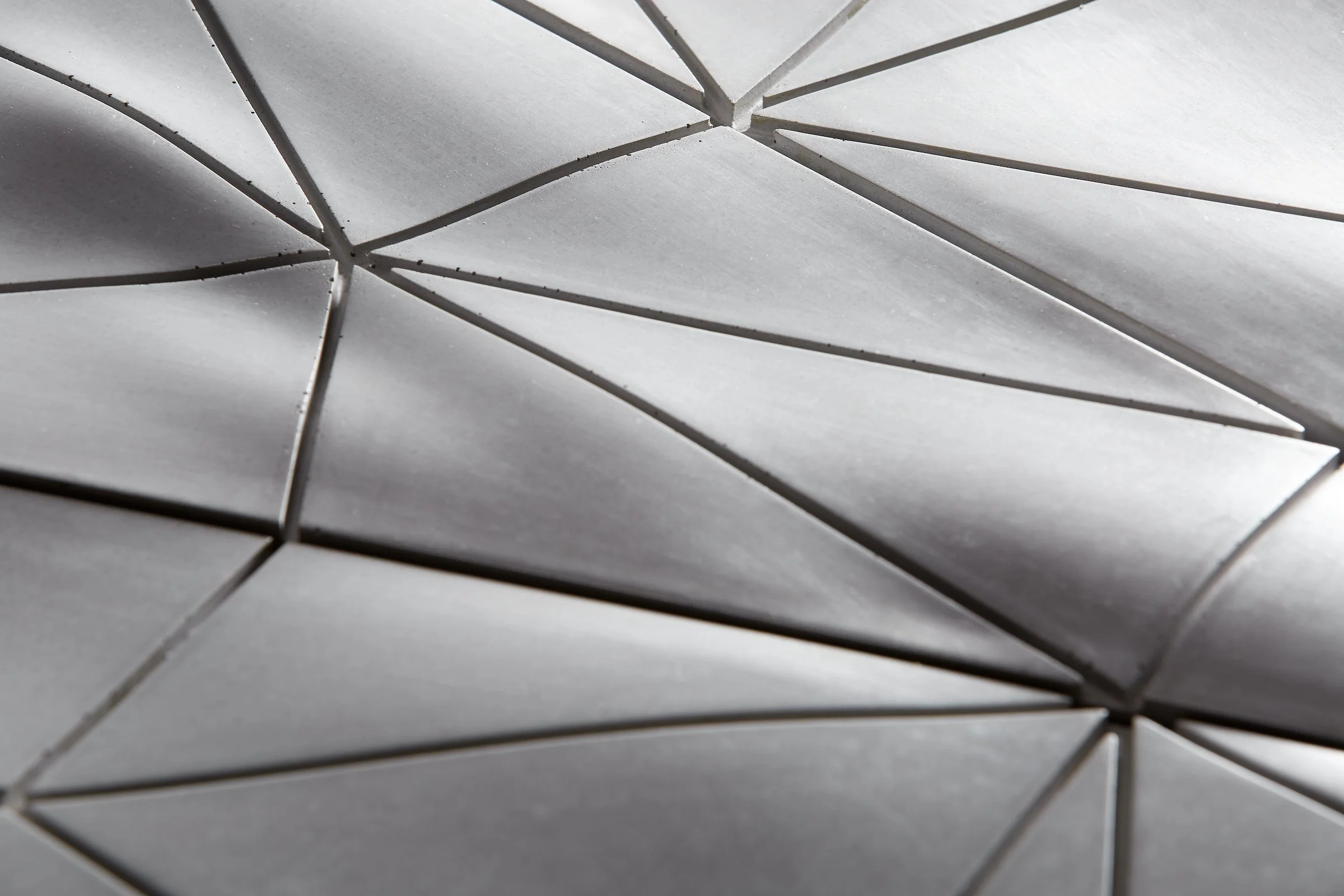 Close-up view of geometric metallic patterns with triangular shapes in silvery gray tones.
