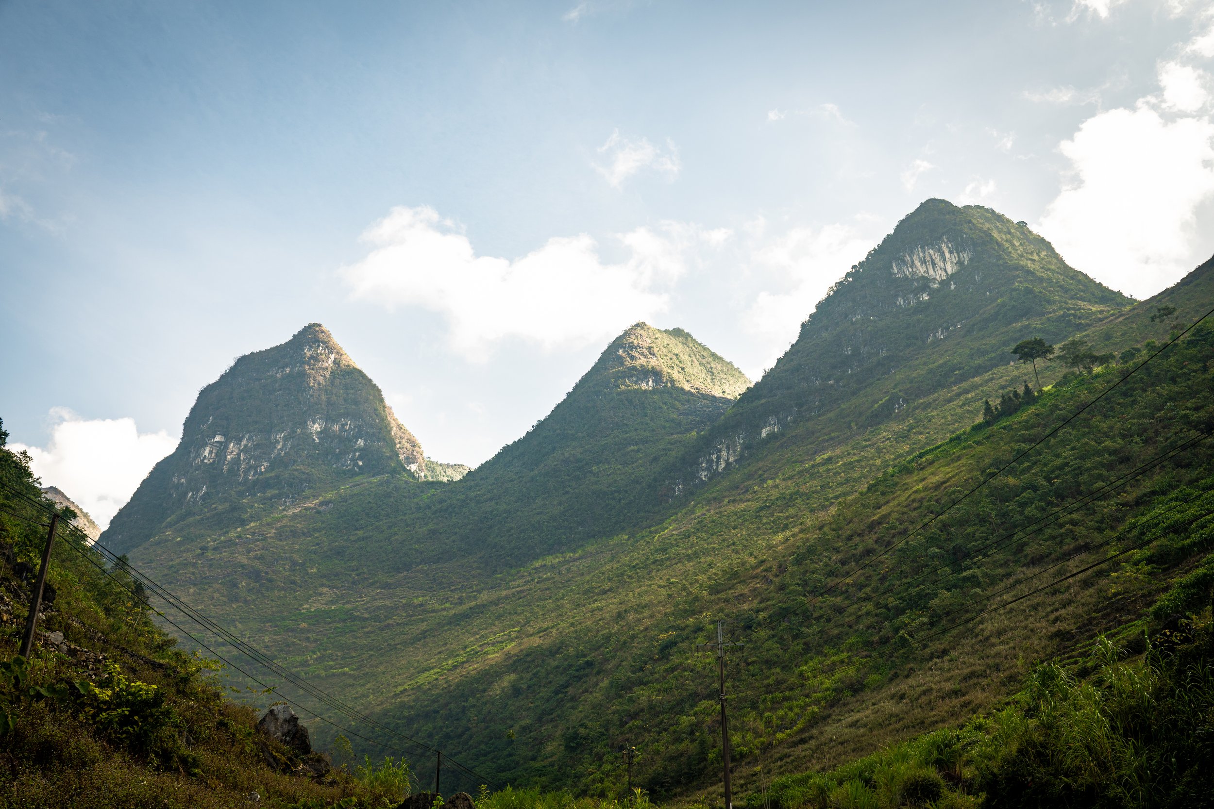 Scenic view of green mountains with steep slopes and a partly cloudy sky.