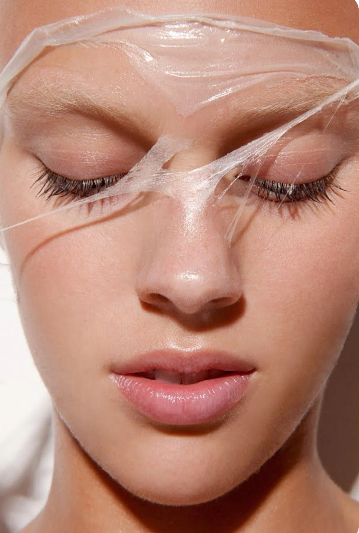 Close-up of a person's face with eyes closed, wearing facial mask or skincare product, and appearing to relax.