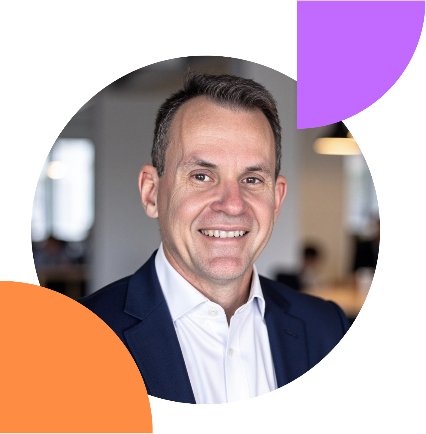 A smiling man in a suit and white shirt in an office setting.