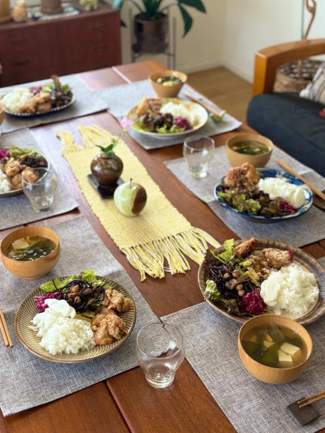 テーブルに置かれた和風の食事セット。ご飯、味噌汁、鶏の唐揚げ、野菜のサラダが各皿に盛られている。