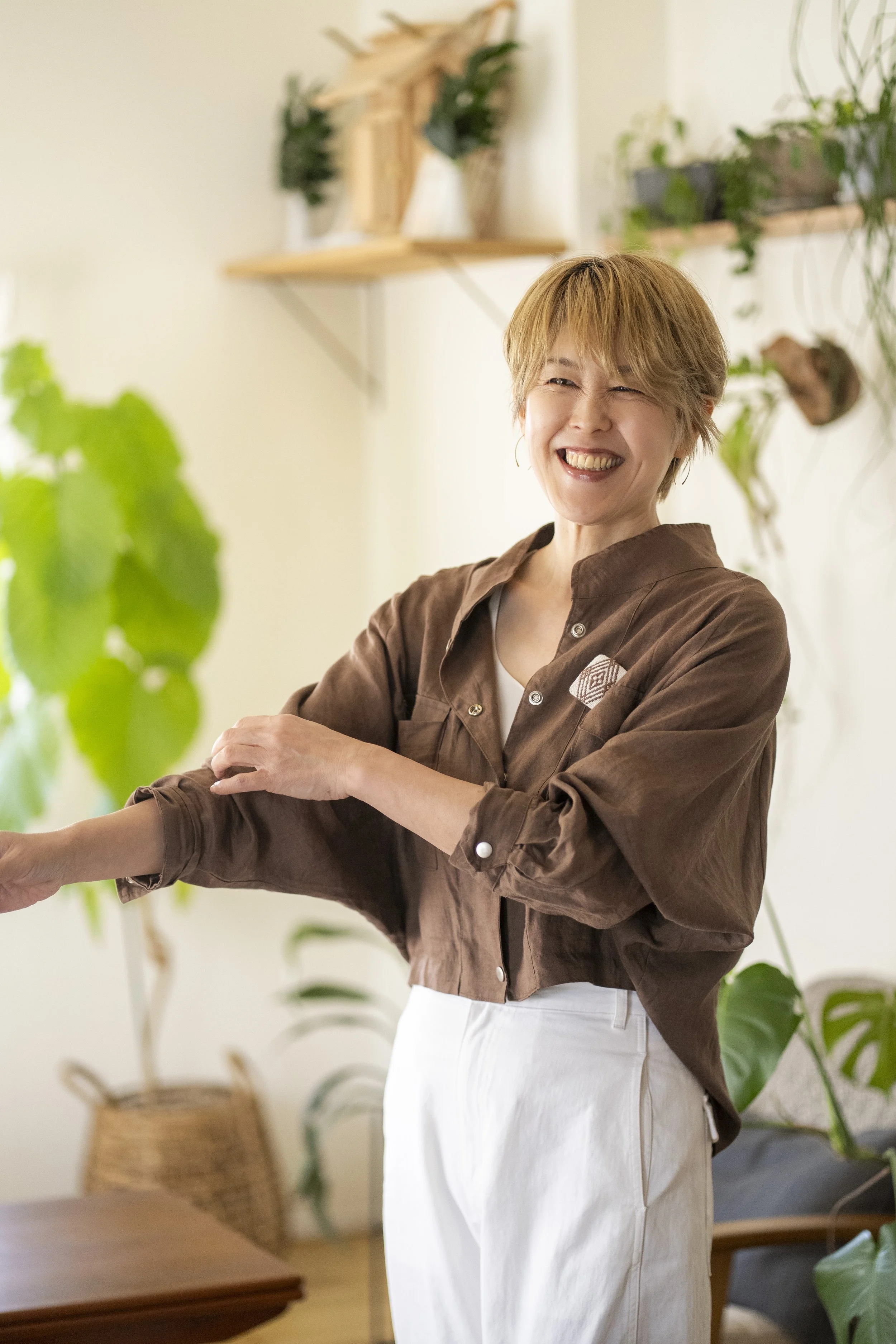 笑顔の女性が室内の植物の前で笑っている写真
