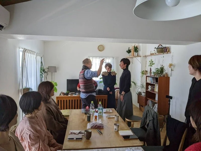 リビングルームで女性たちが会話し、2人の男性が立ち話をしているグループの写真。
