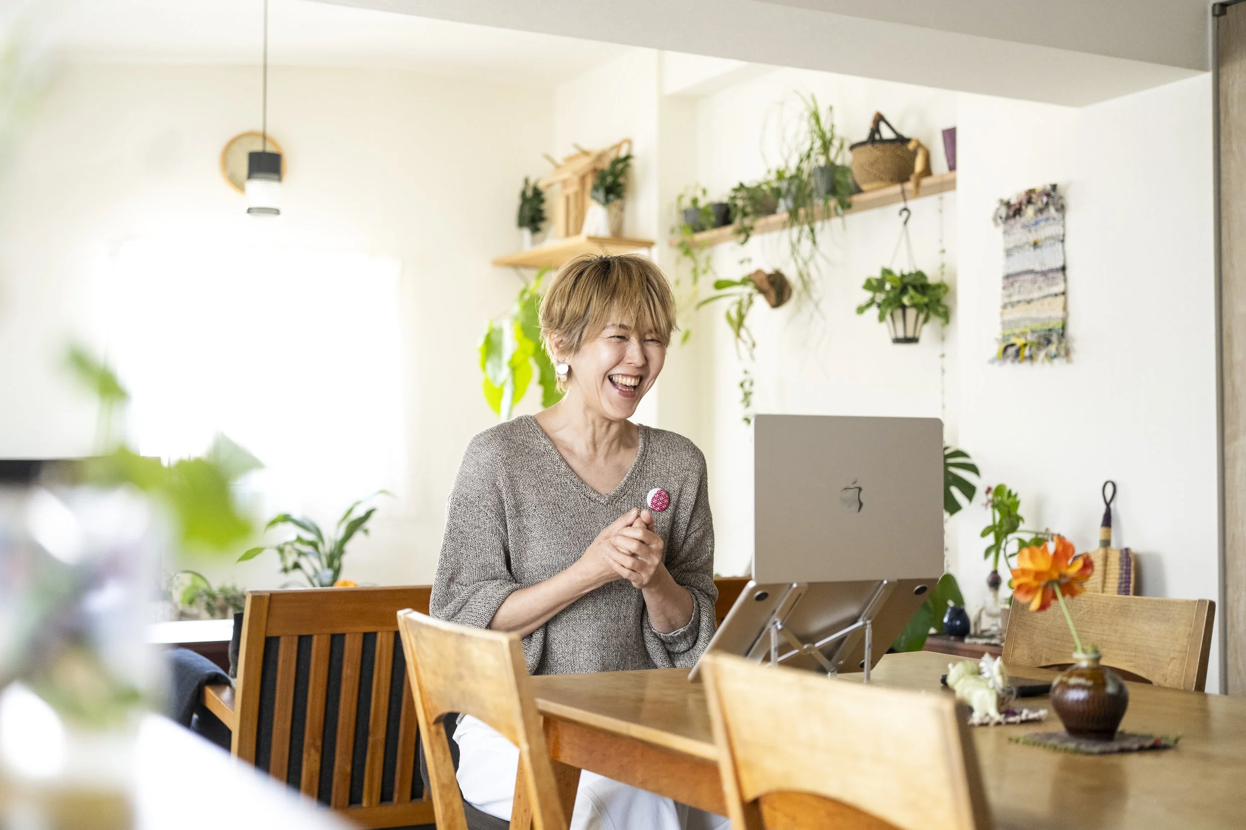 笑顔の中年女性がパソコンの前で祈るように手を合わせている。