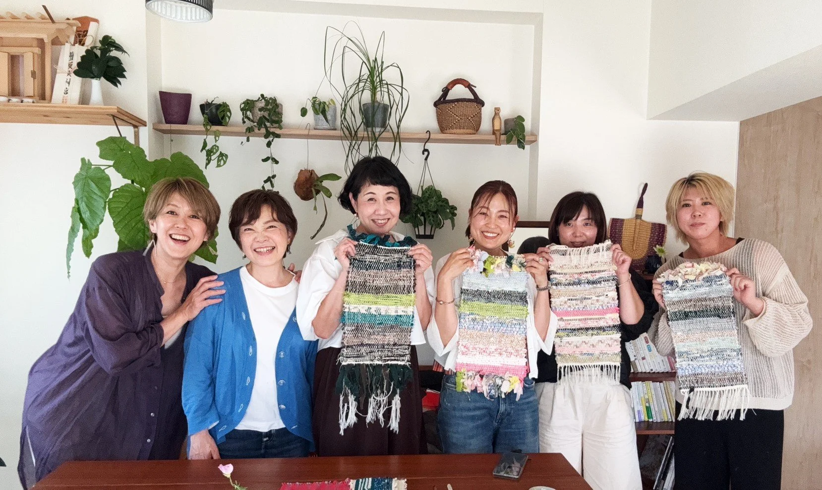 ソファの前で笑顔の女性たちがカラフルな織物を持っている写真