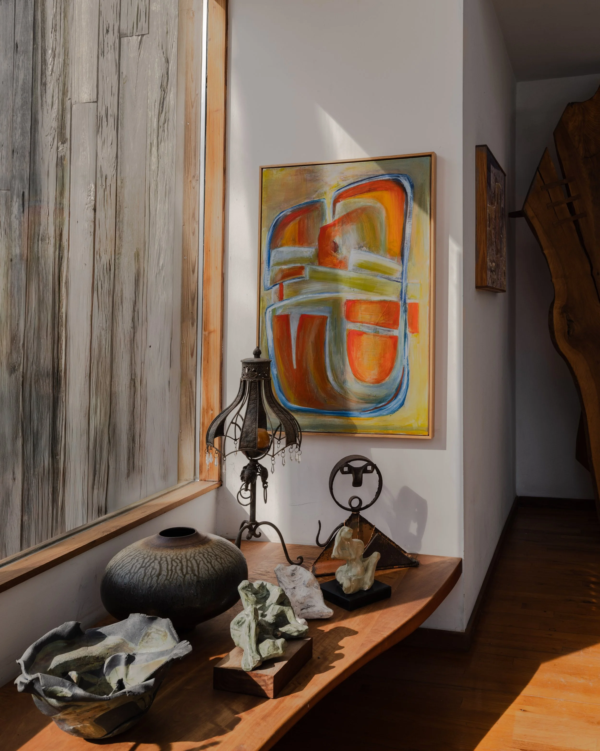 Interior editorial photography of McElroy House in Malvern PA, featuring entryway vignette with abstract artwork, sculptural objects, and warm natural light.