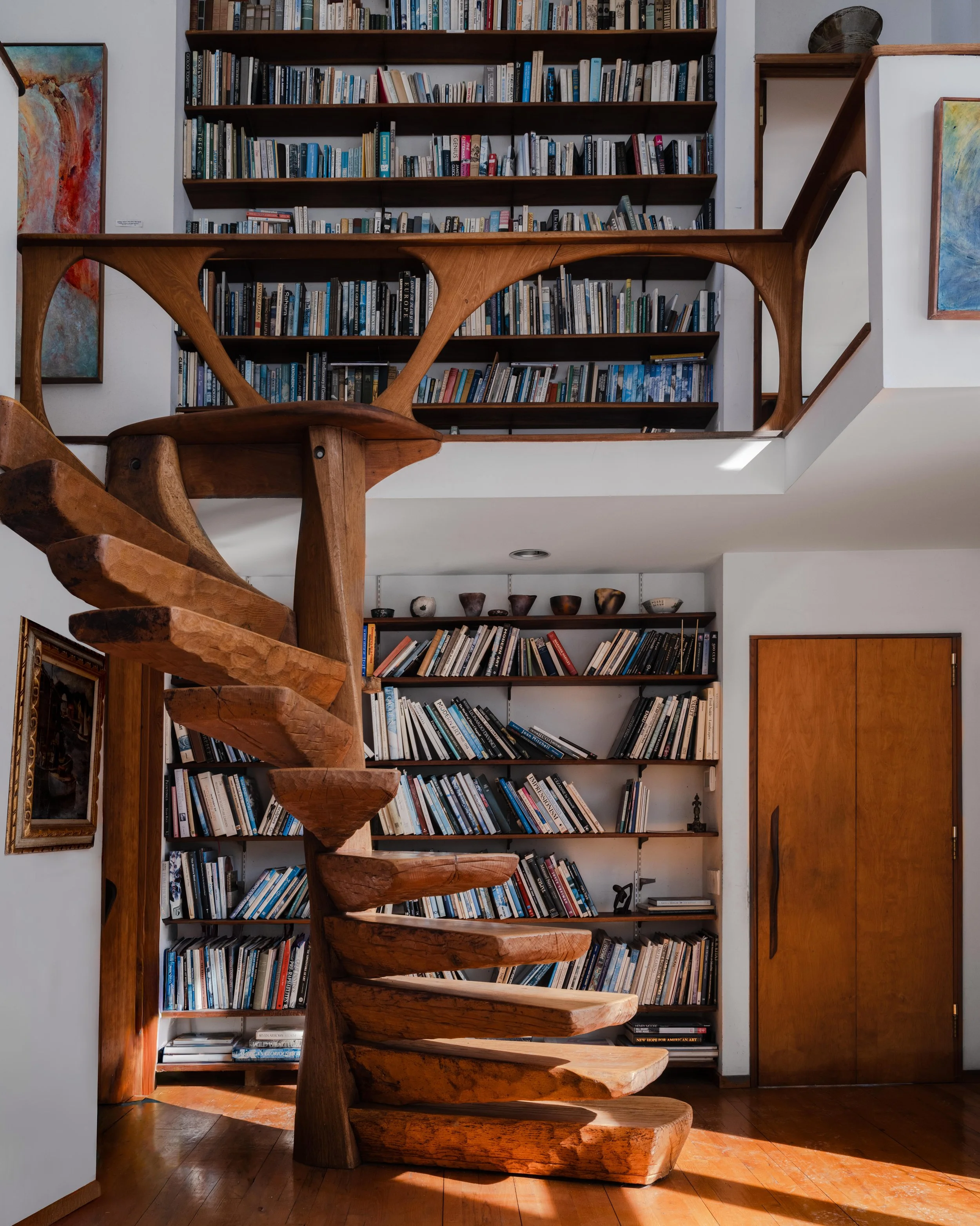 Sculptural wooden spiral staircase with floor to ceiling bookshelves at McElroy House in Malvern PA — interior and architectural photography