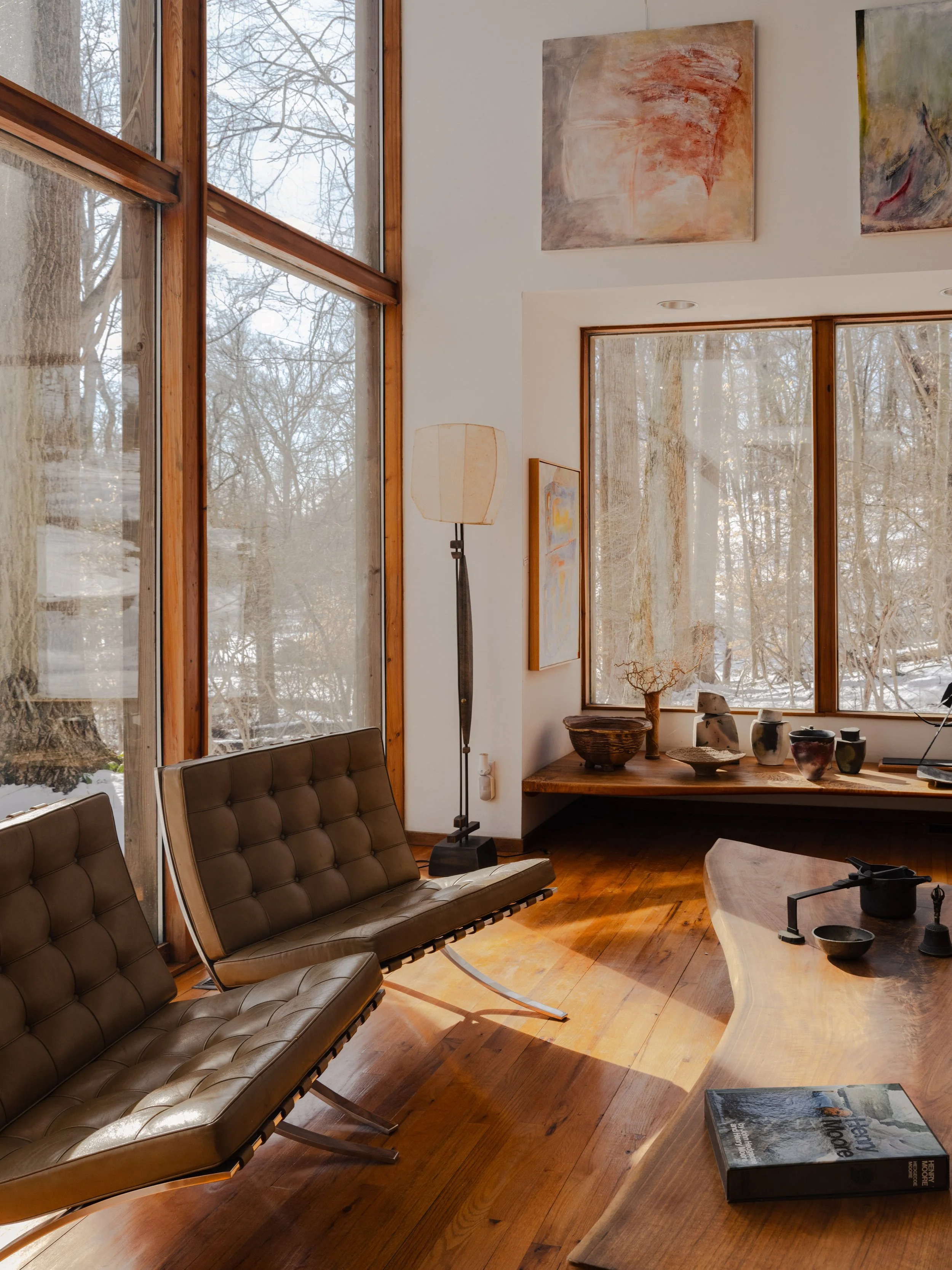 Interior editorial photography of McElroy House in Malvern PA, featuring sunlit modern living room, floor-to-ceiling windows, and mid-century modern seating.