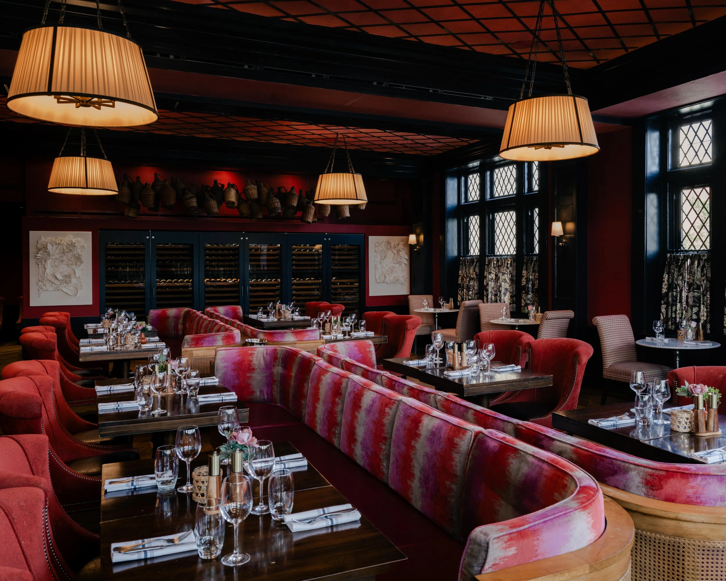 Modern restaurant interior with deep red walls, large abstract artwork, and warm pendant lighting above a marble table, styled dining setting with upholstered chairs and intimate ambiance, editorial interior design photography in the Philadelphia are