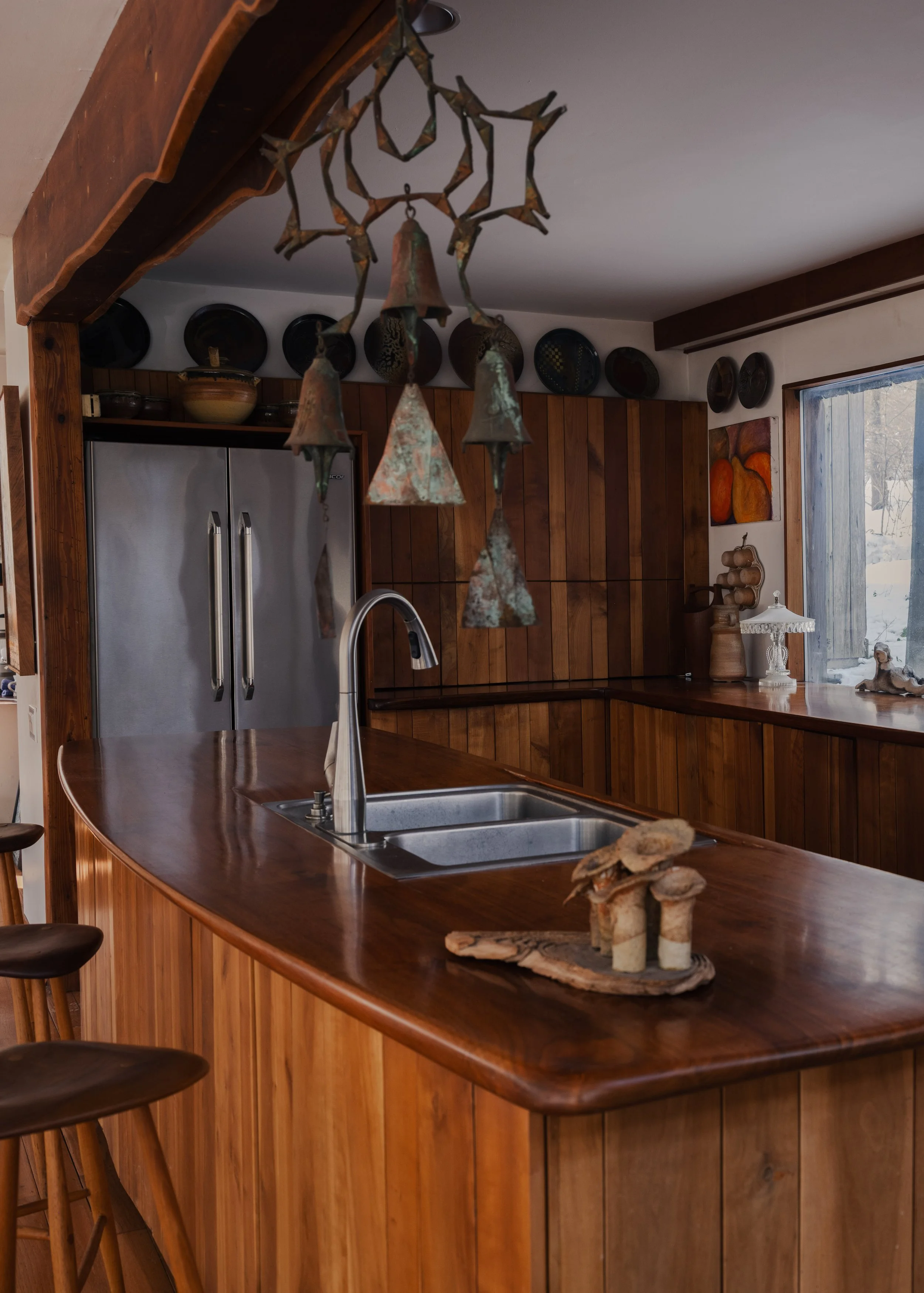 Interior editorial photography of McElroy House in Malvern PA, featuring custom wood kitchen with curved island, natural materials, and sculptural lighting.