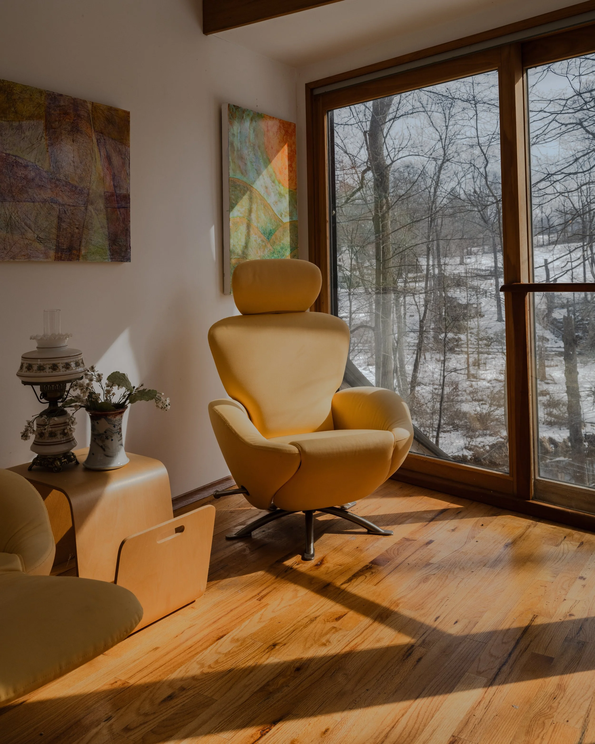 Editorial interior design photography of McElroy House in Malvern Pennsylvania featuring a sculptural yellow lounge chair, warm wood flooring, and natural window light