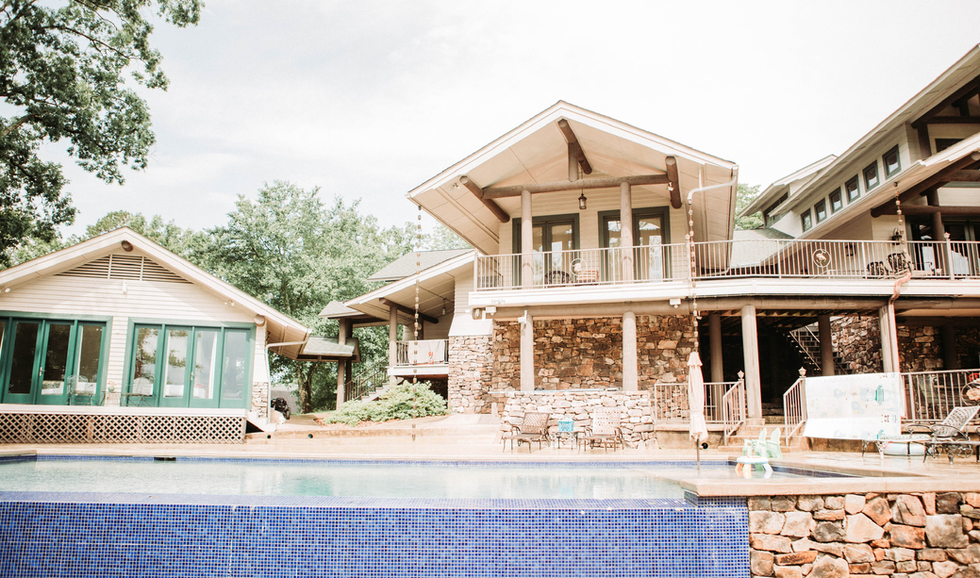 Residential house with large balcony overlooking a swimming pool, surrounded by trees.
