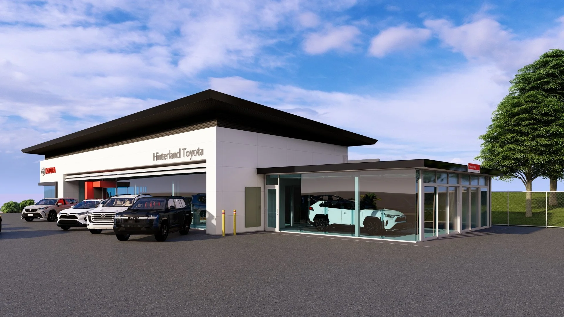 A modern car dealership building with the sign "Hinterland Toyota"; several cars parked in front and inside the showroom, including a white vehicle inside a glass-walled section; a clear blue sky with some clouds, nearby trees, and a fenced grassy area.