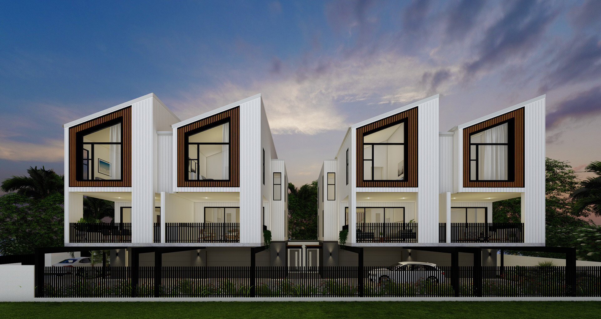 Modern white multi-level houses with large front windows, black accents, and wooden framing, surrounded by greenery and a black fence, during sunset.