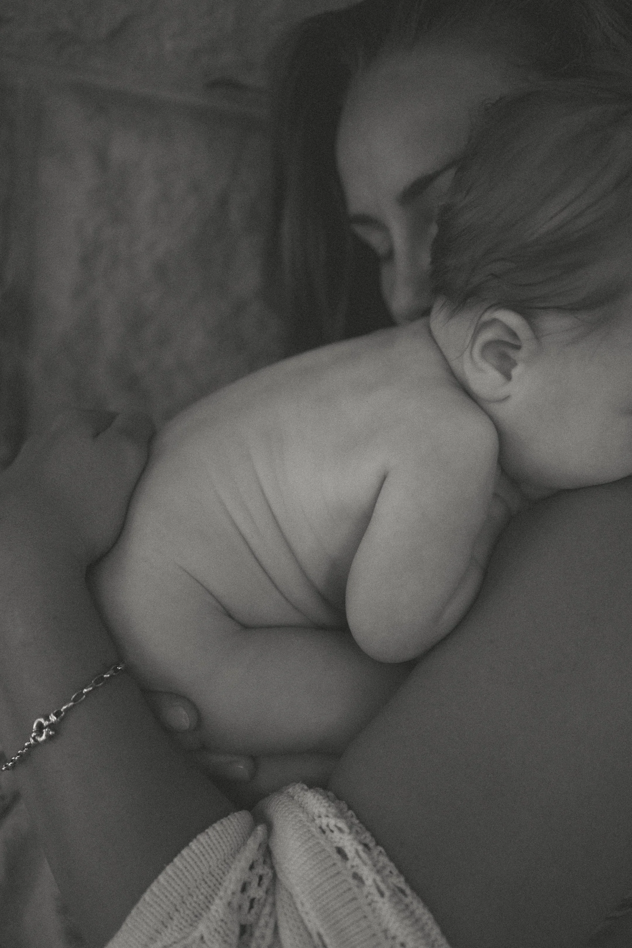 A woman comforting a sleeping baby with their face close together in a tender moment.