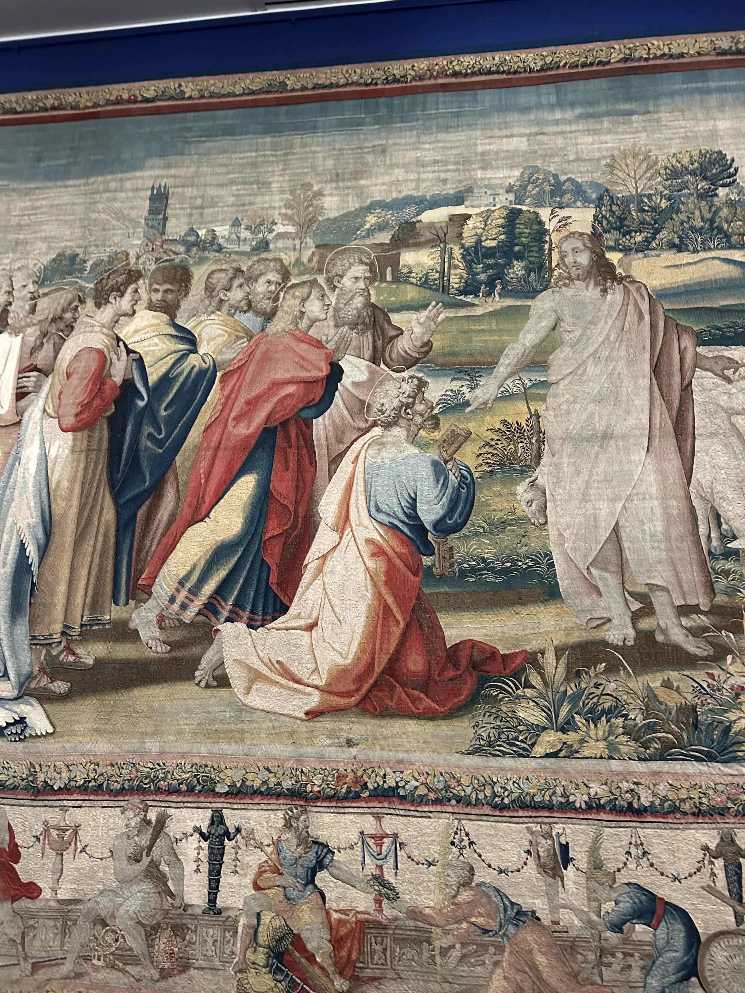 A religious mural depicting Jesus Christ crucified, surrounded by a group of people including apostles or followers, set in a landscape with trees and buildings in the background.