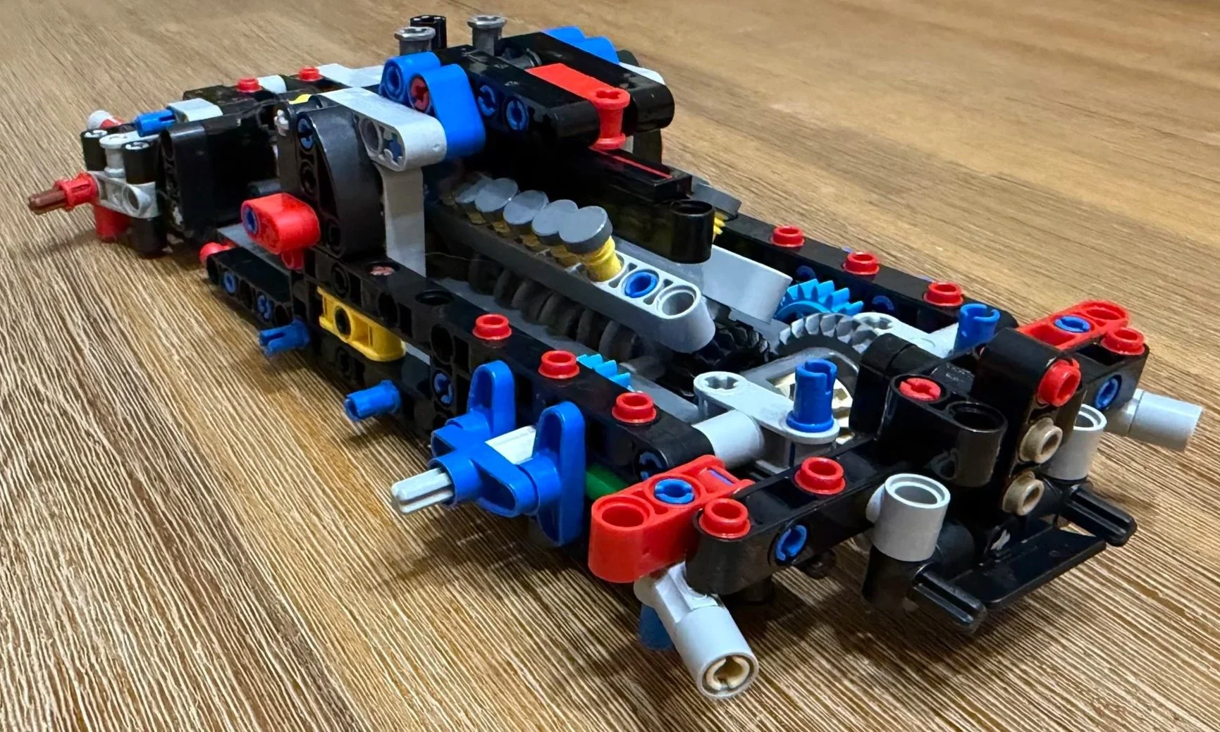Ferrari FXX K chassis with the V12 engine installed, exposing gray piston tops, yellow springs, gears, and the rear frame.