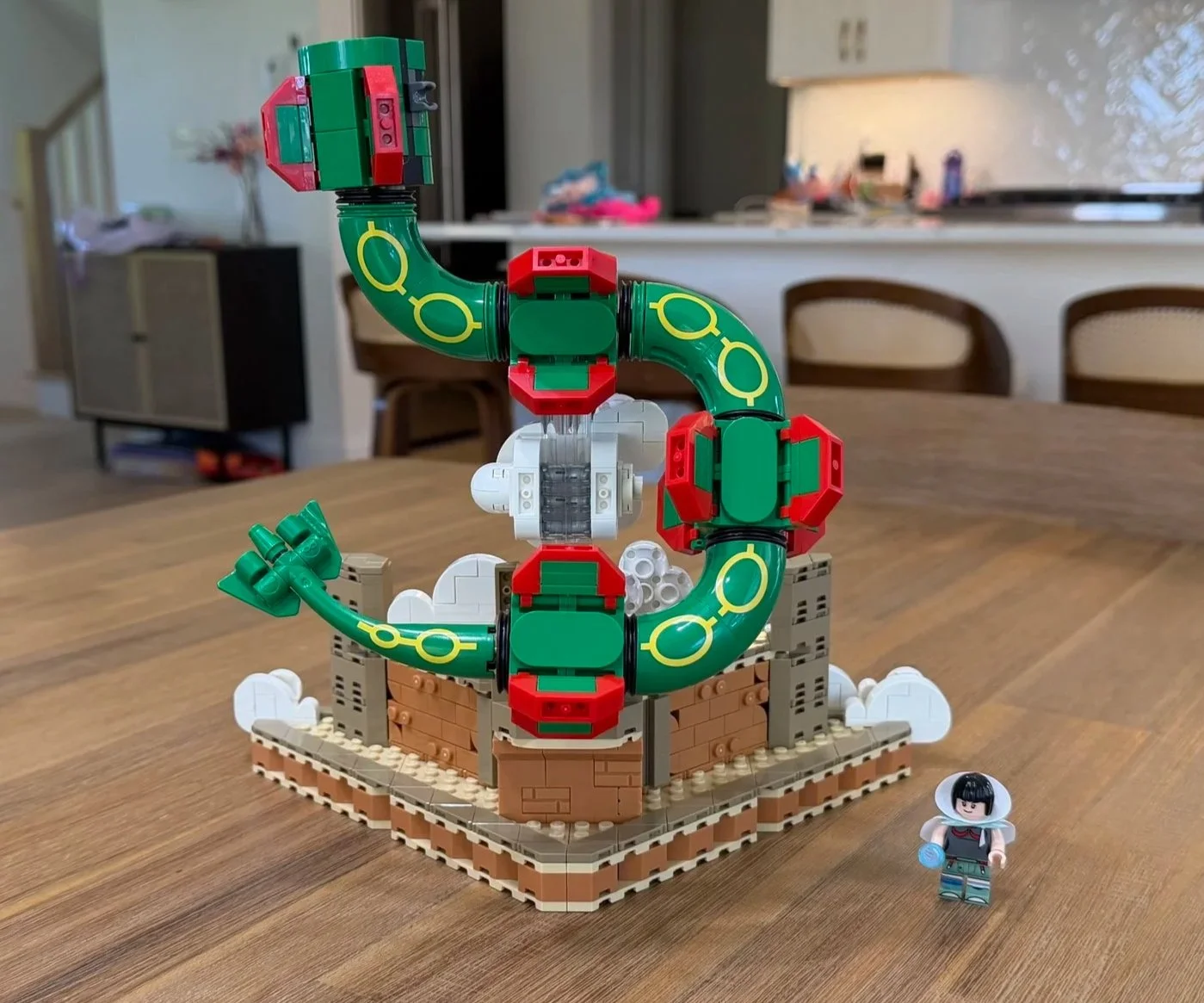 Rear view of the unfinished Rayquaza body and tail, with green curved sections, red fins, and a visible clear support.