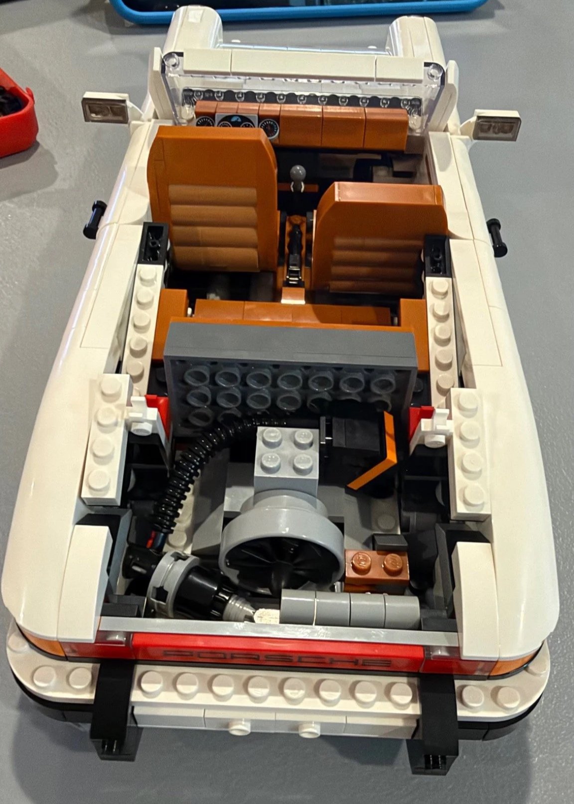 Exposed rear engine assembly and brown seats in a white LEGO Porsche during rebuilding.