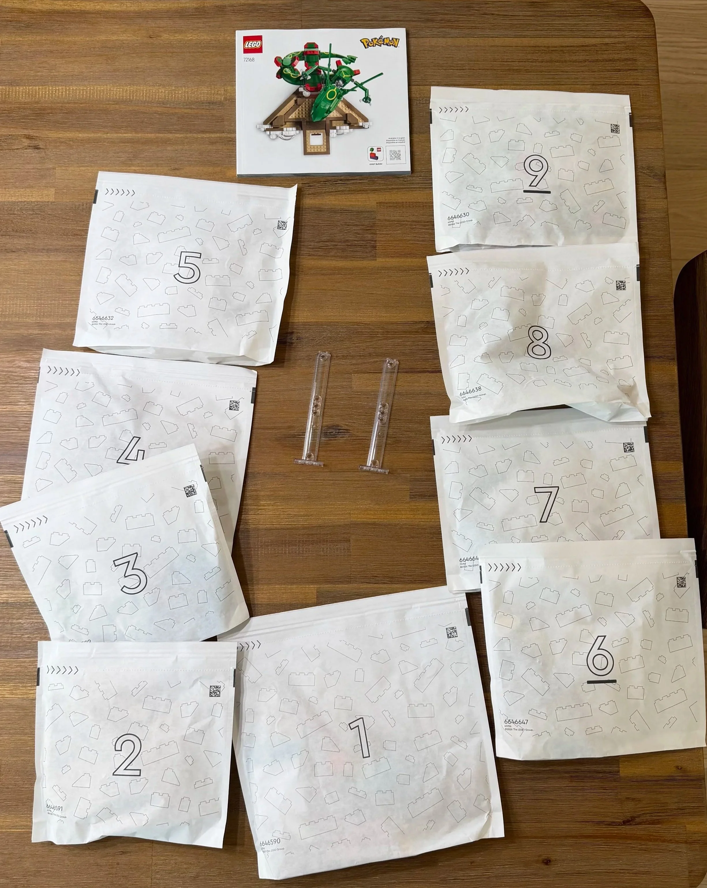 Rayquaza 72168 instruction booklet, nine numbered paper bags, and clear support pieces arranged before building.