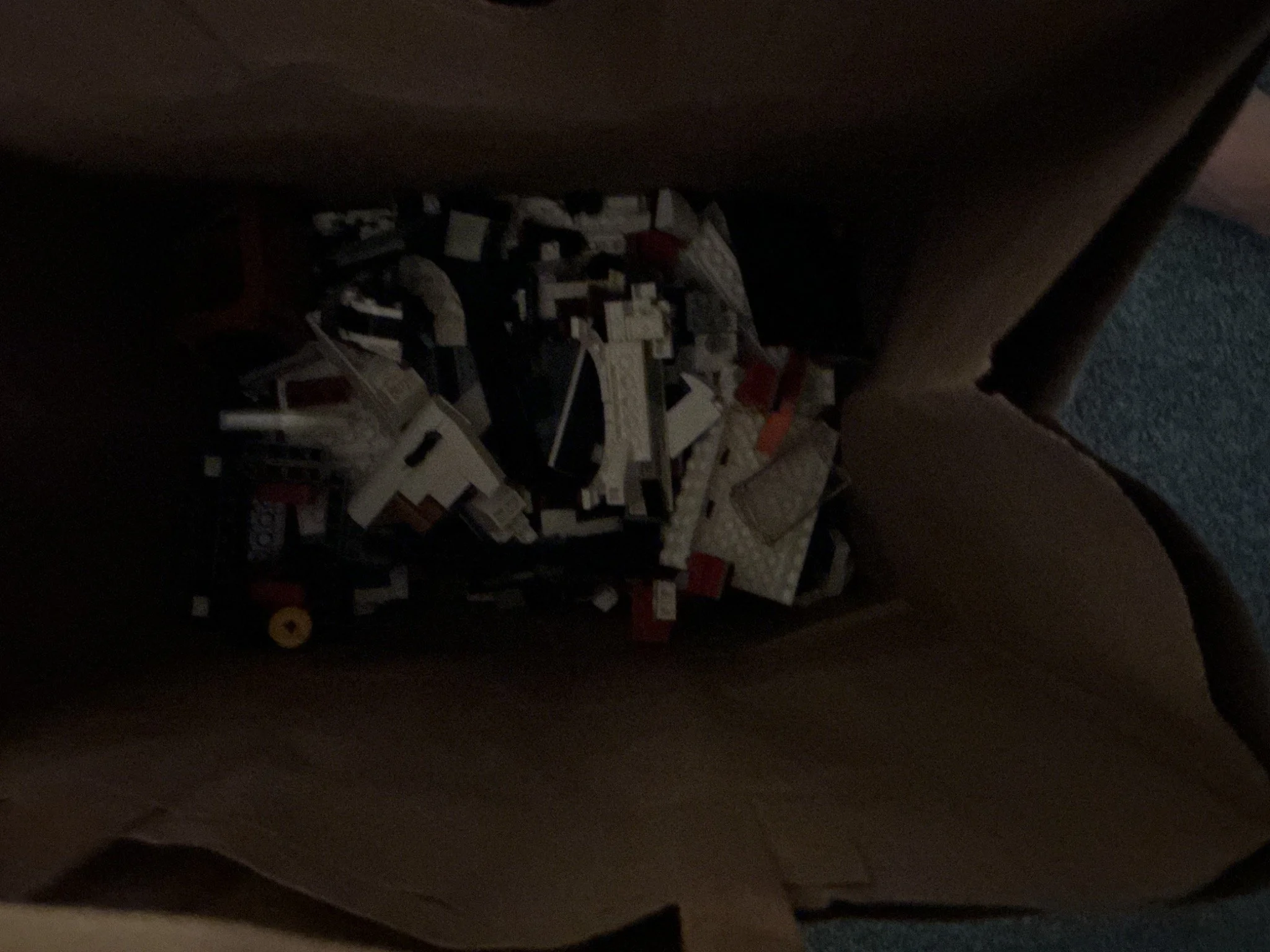 Separated white LEGO Porsche body sections and loose pieces inside a cardboard box before rebuilding.