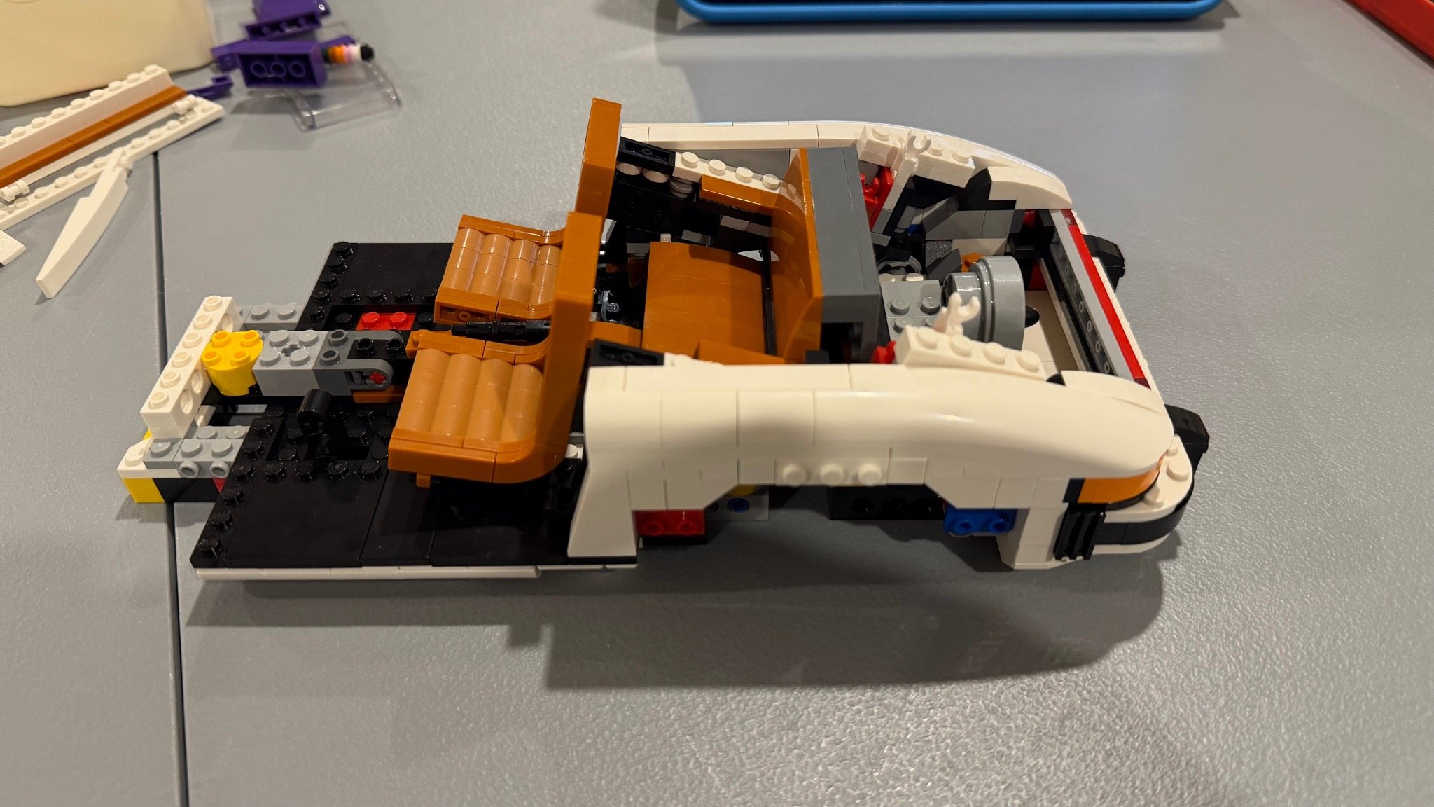 Partly rebuilt white LEGO Porsche with brown front seats, rear seating and exposed chassis.