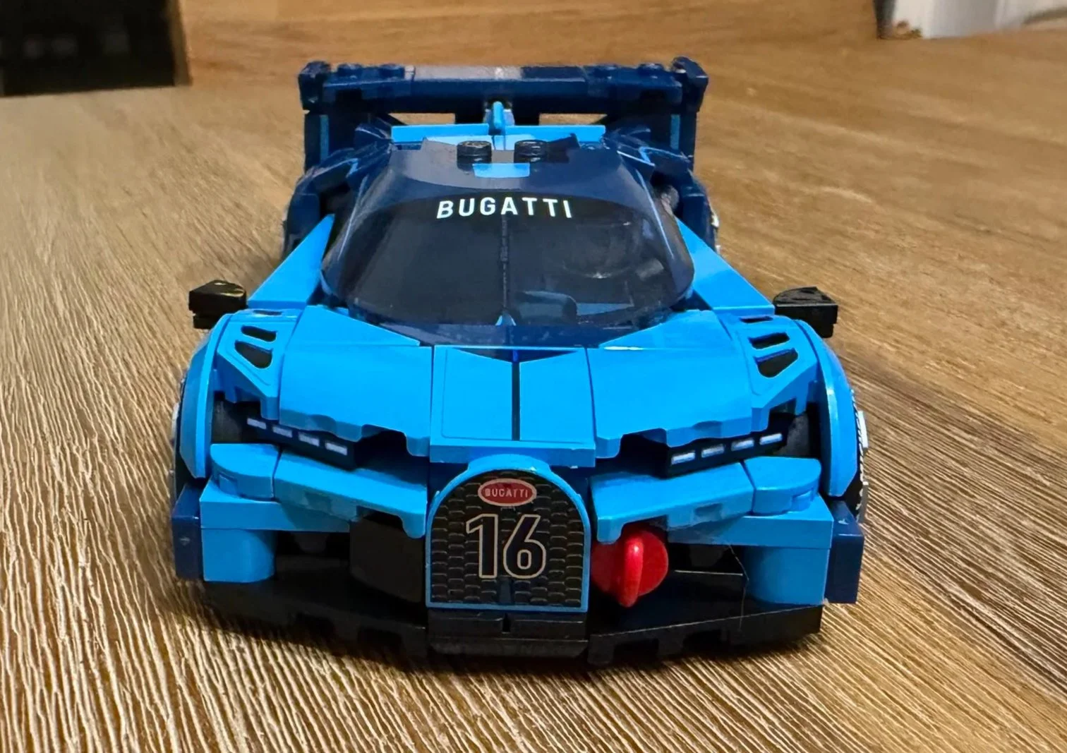 Front view of the completed LEGO Bugatti showing the number 16 horseshoe grille, headlights, blue hood, and curved windshield.
