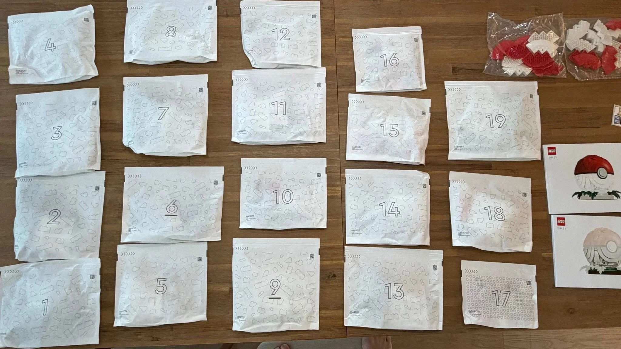 Numbered LEGO Pokémon Poké Ball bags and instruction booklets arranged before building.