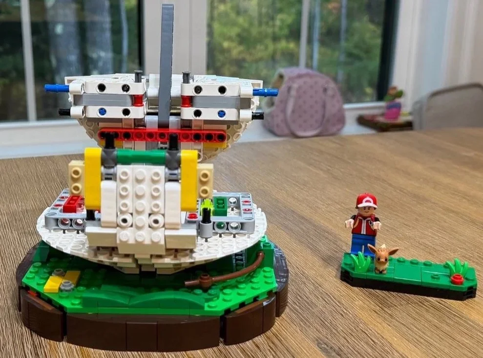 Lower Poké Ball Technic frame with blue pins and white shell structure in progress.