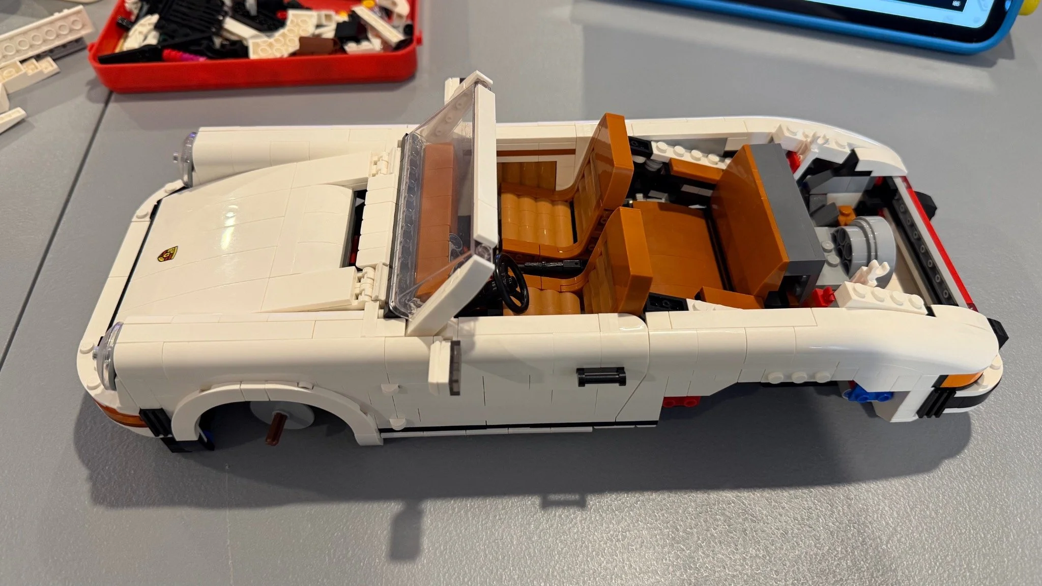 Partly rebuilt white LEGO Porsche with front bodywork and windscreen fitted and brown seats visible.