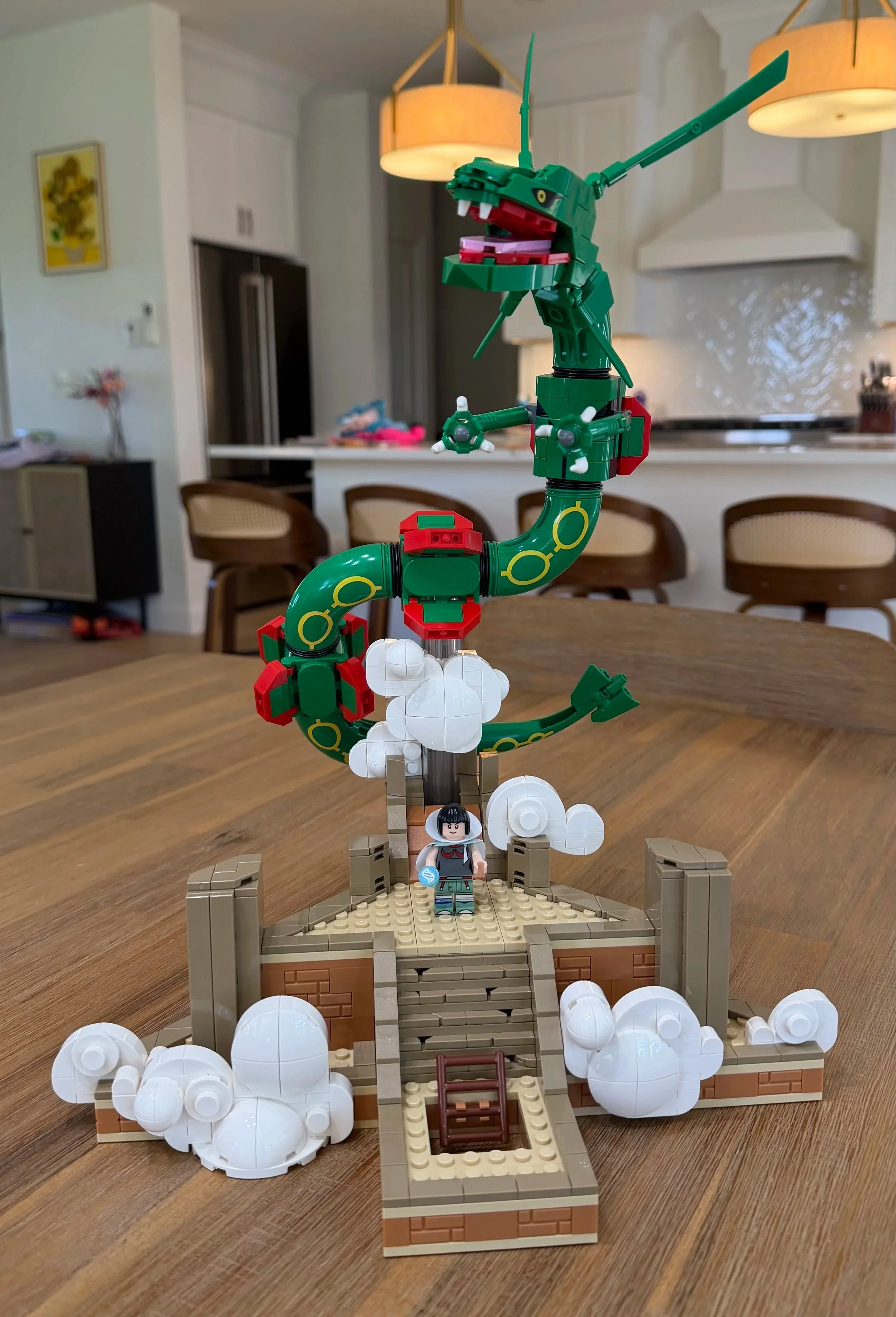 Completed LEGO Rayquaza 72168 above Sky Pillar, with an open mouth, curved green body, white clouds, and Zinnia on the platform.