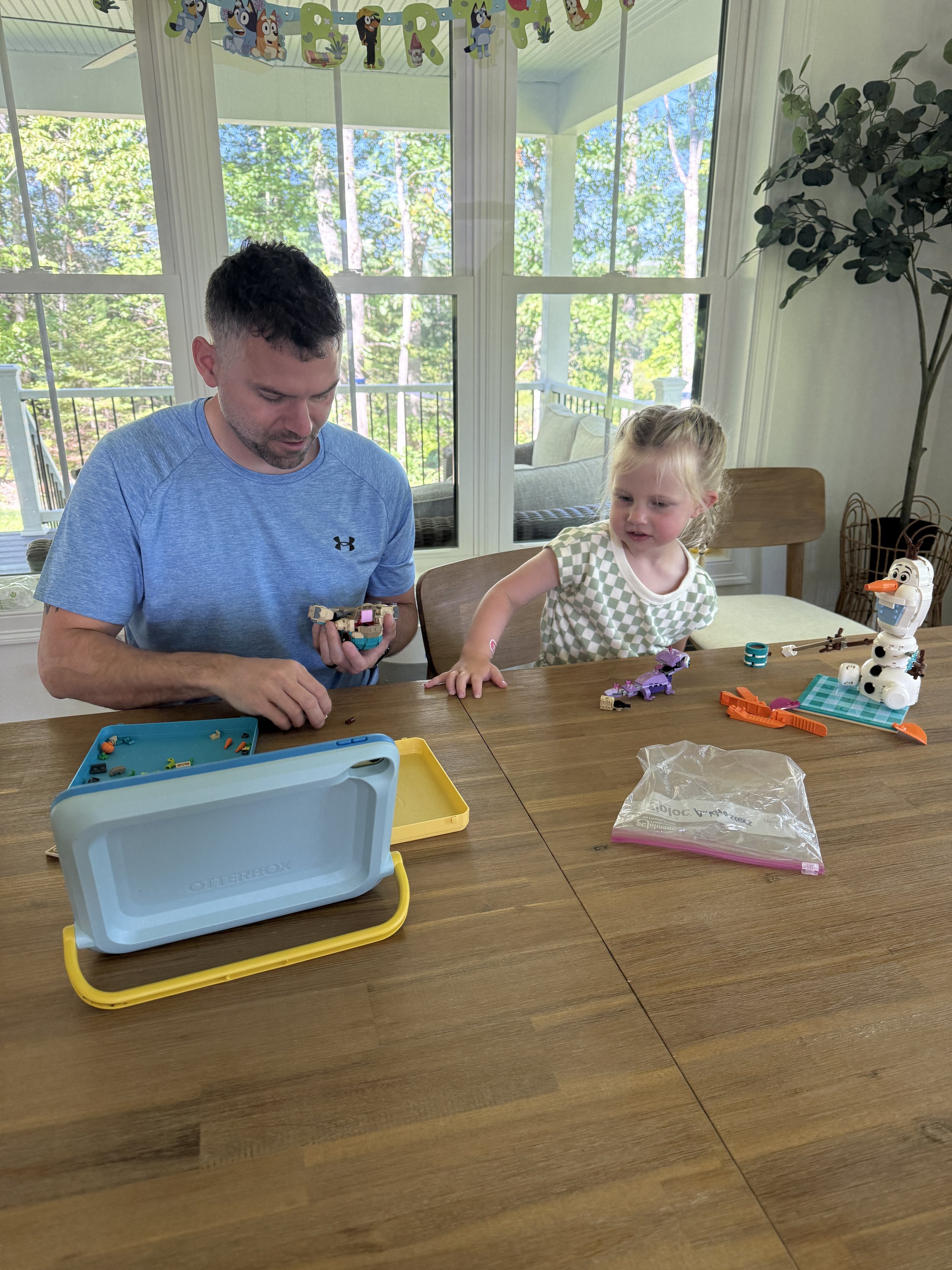 Josh, owner of The Bricksmith, building LEGO models with his niece at a table.