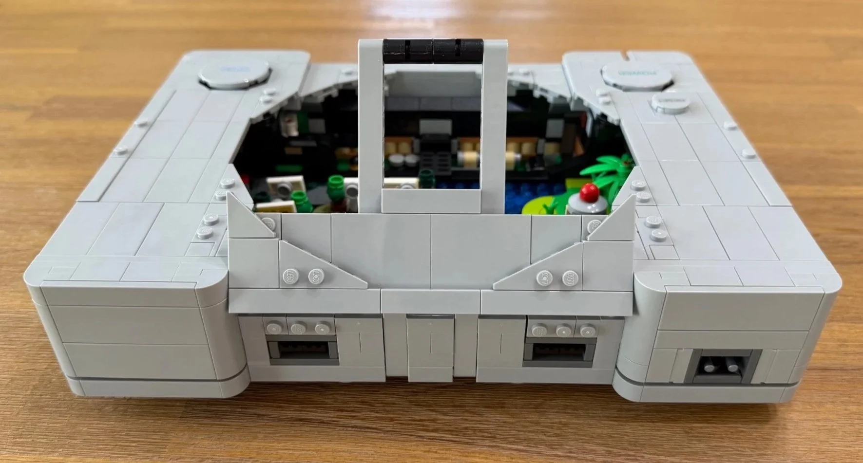 Technic arm for the LEGO PlayStation disc lid rising from the rear of the unfinished console.