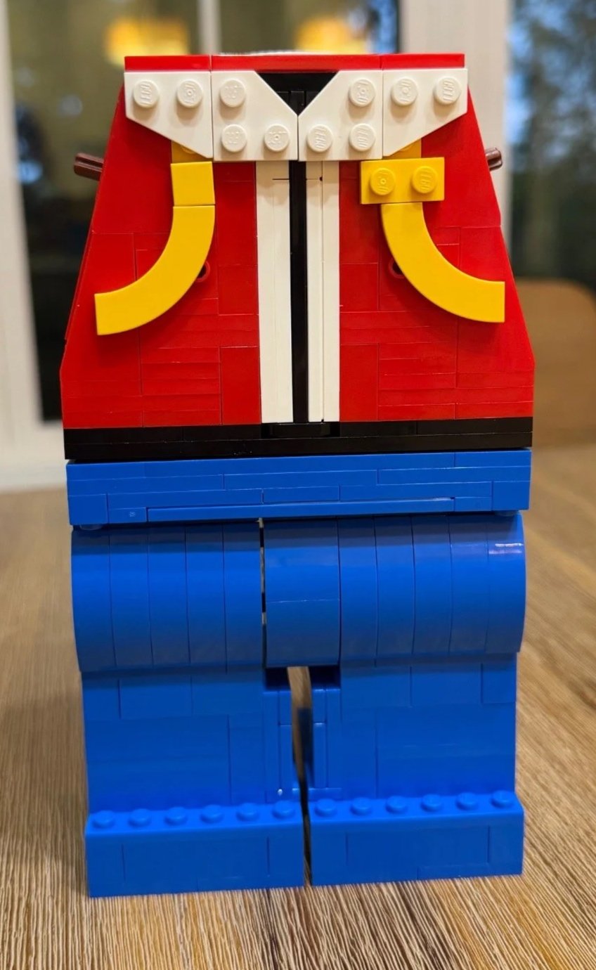 Front of LEGO Red's headless torso attached to blue legs, with a white collar, white center detail, and curved yellow straps.