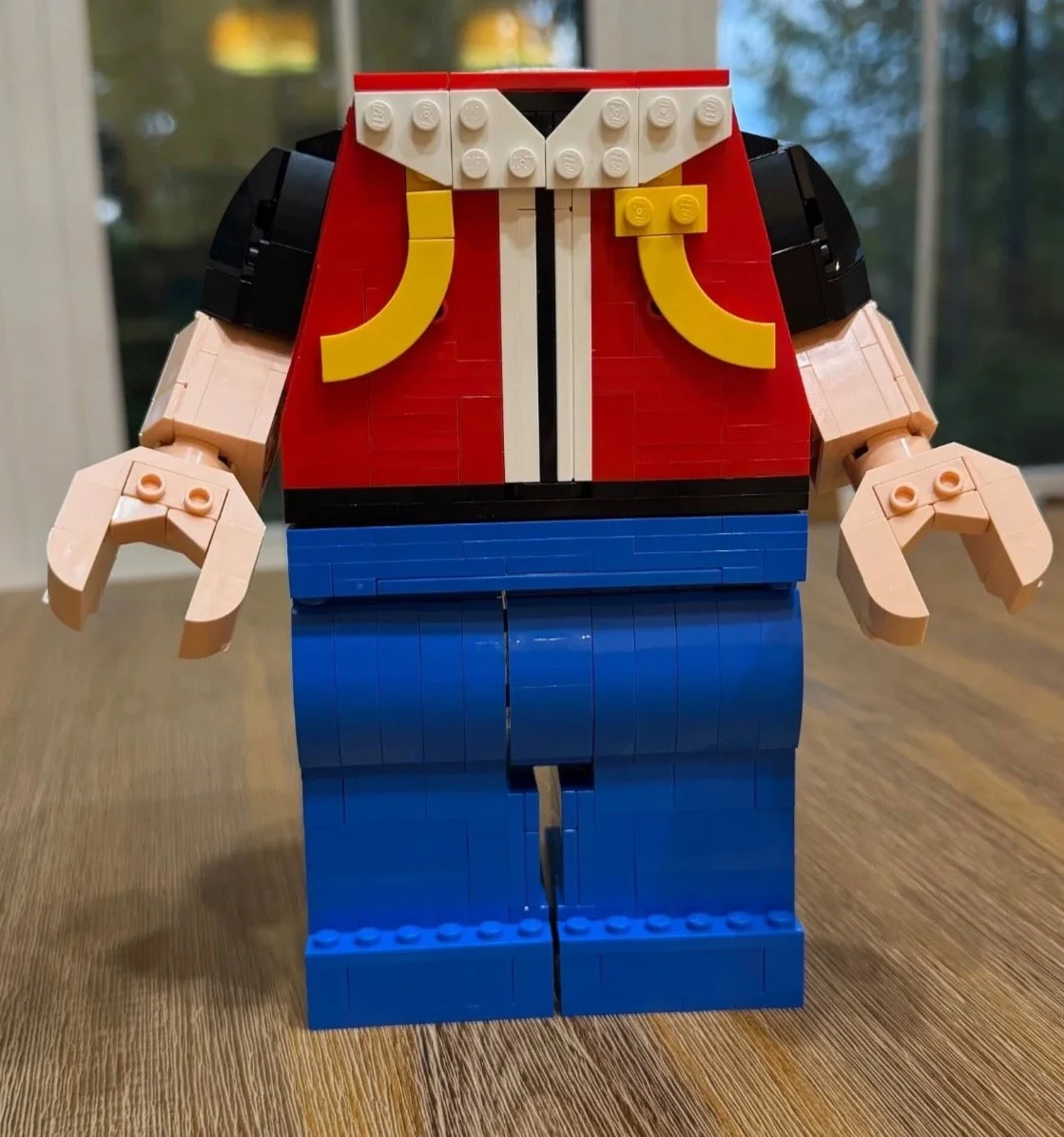 Headless LEGO Red figure with both skin-colored arms, rounded black sleeves, and large claw-shaped minifigure hands attached.
