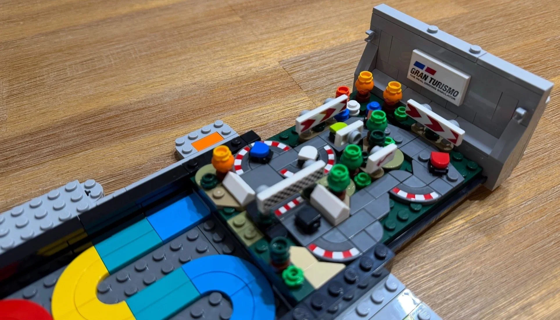 Gran Turismo micro racing scene with tiny cars, track barriers and checkered details.