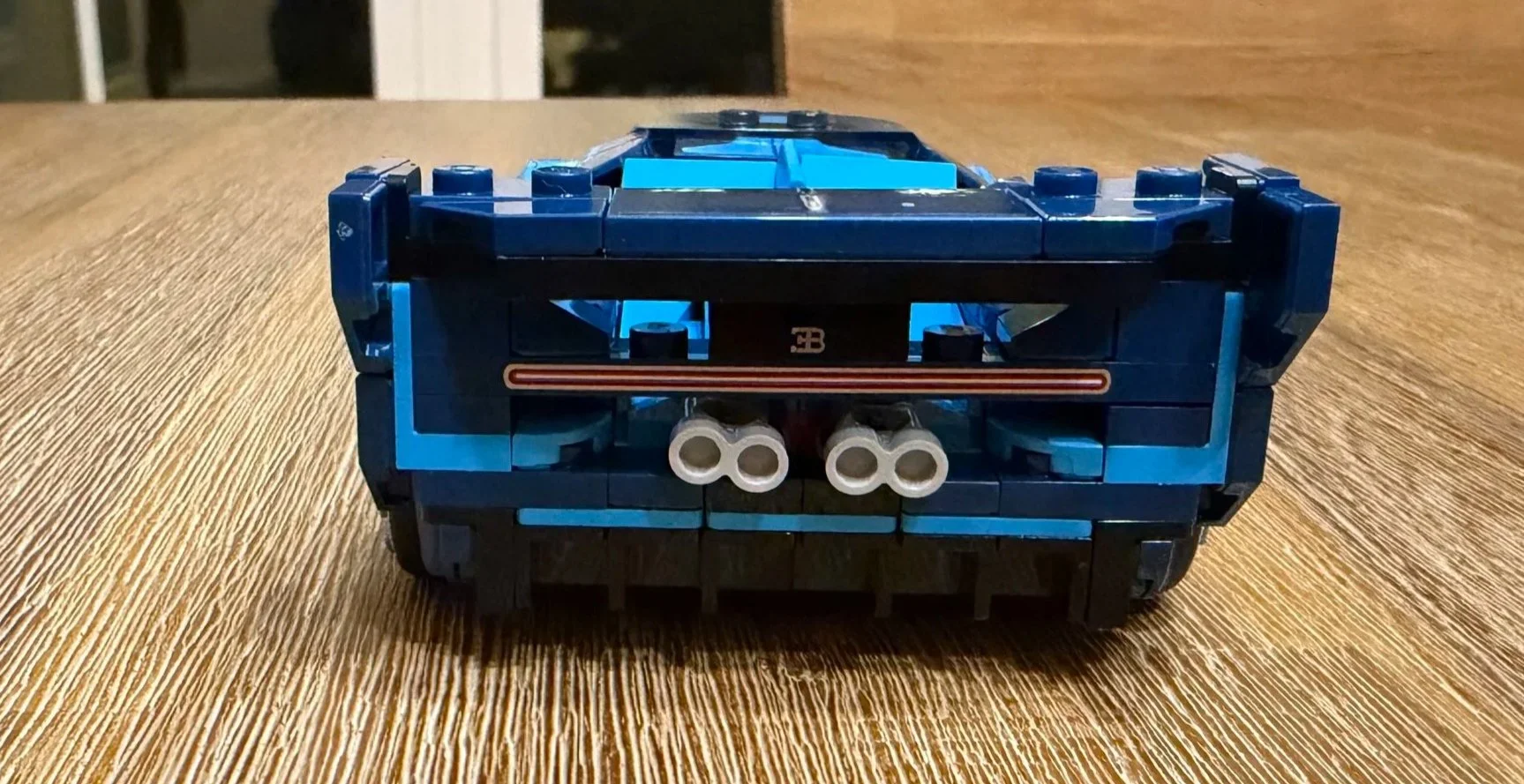 Rear view of the completed LEGO Bugatti with its wide wing, narrow red taillight strip, and four silver exhaust outlets.