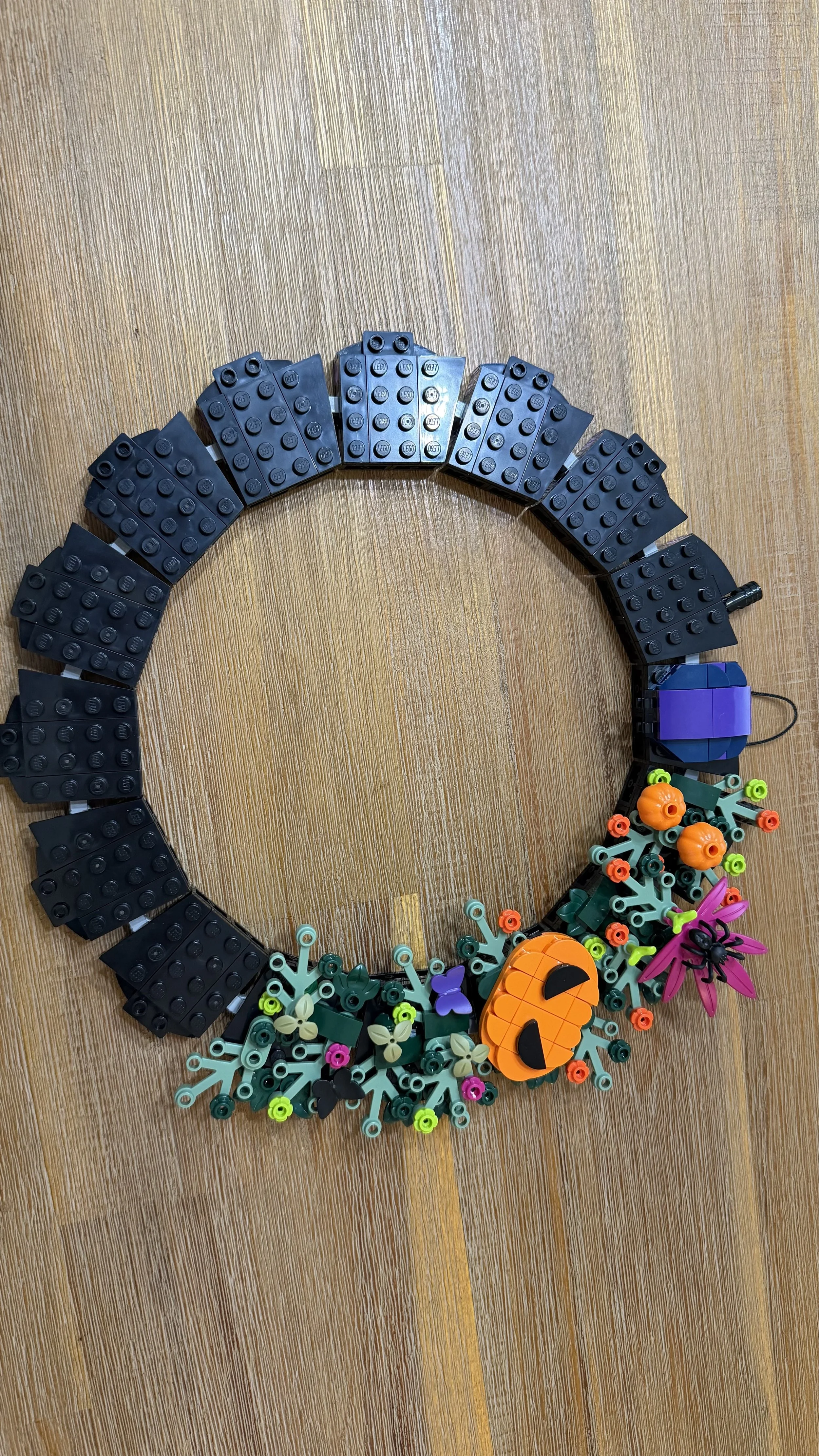 Partially decorated LEGO Halloween Wreath with pumpkins, flowers, and spider
