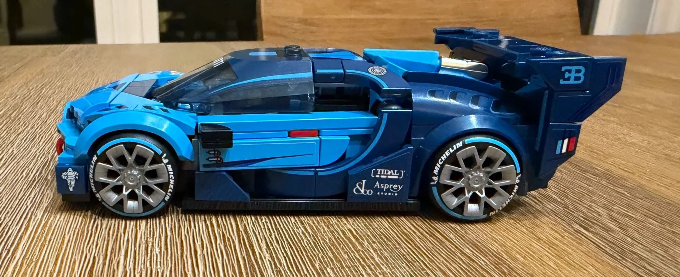 Side view of the finished blue LEGO Bugatti Vision GT 77253 with silver rims, Michelin-branded tyres, and a large rear wing.