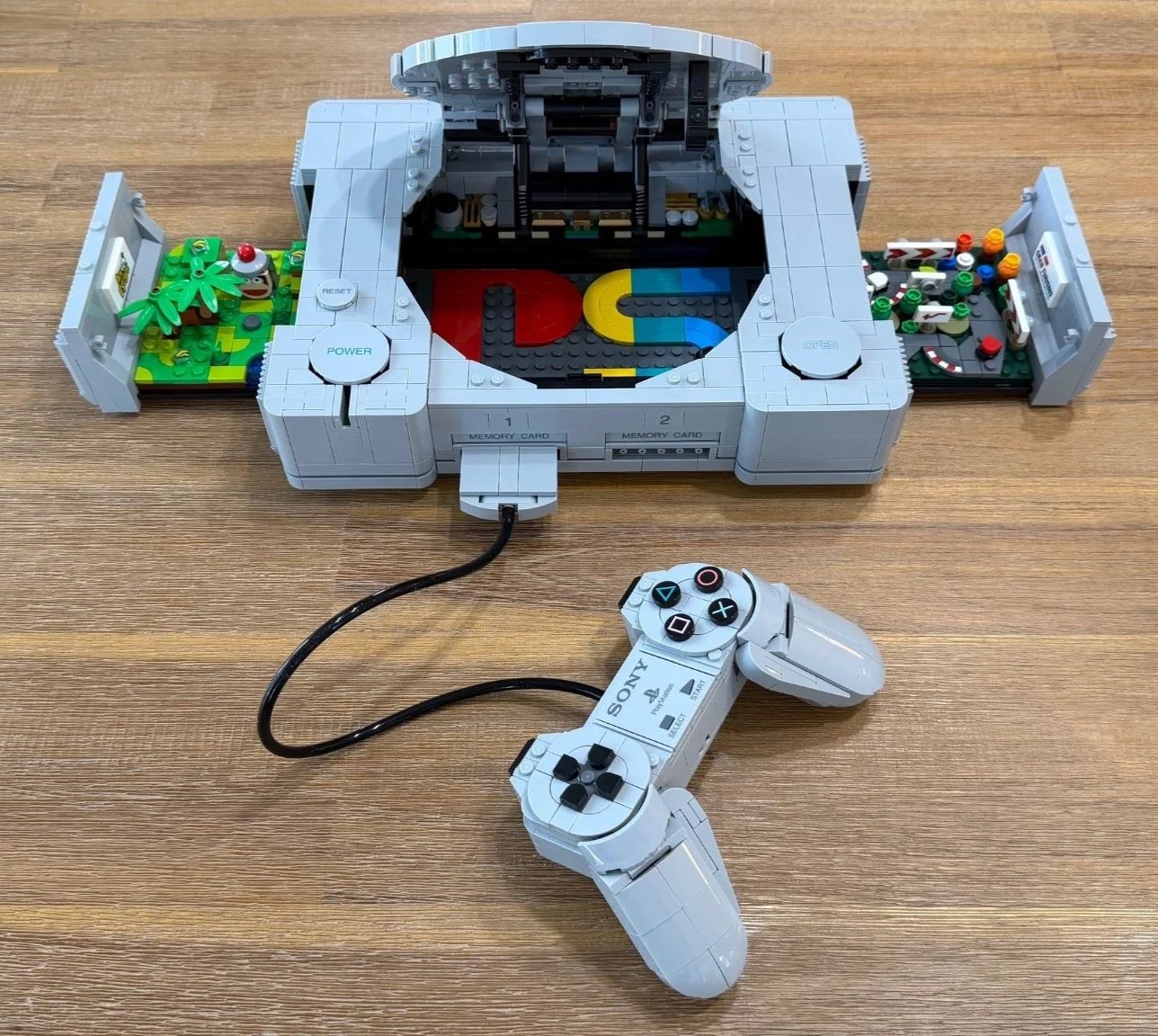 LEGO PlayStation with its lid open, Gran Turismo and Ape Escape scenes removed to either side, and the controller connected at the front.