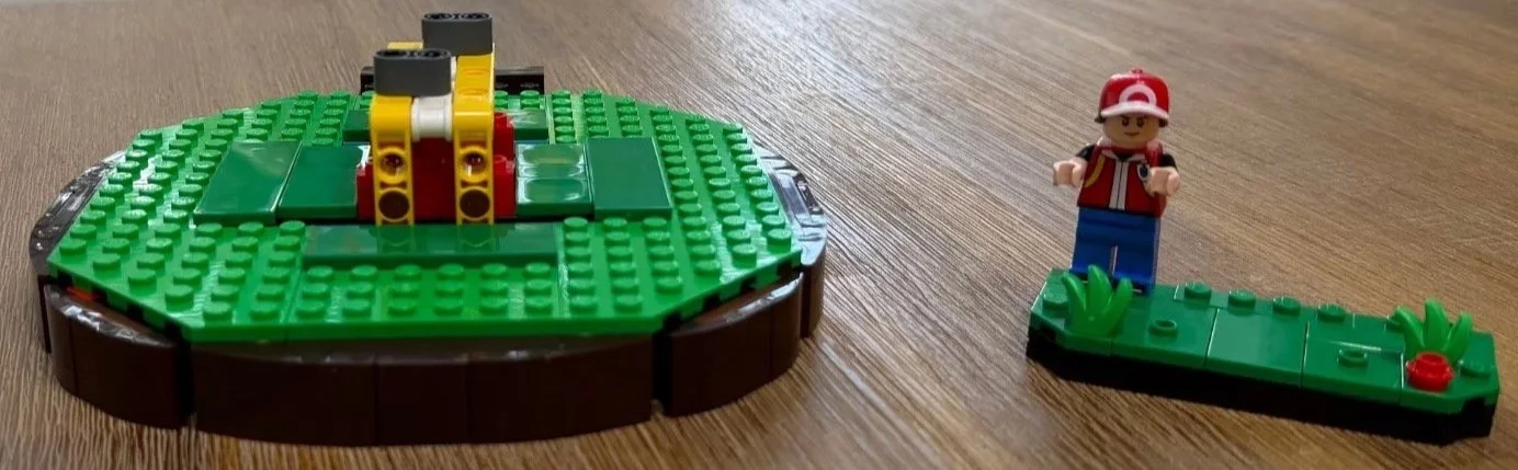 Green plates and brown sloped edges on the early LEGO Poké Ball display base.