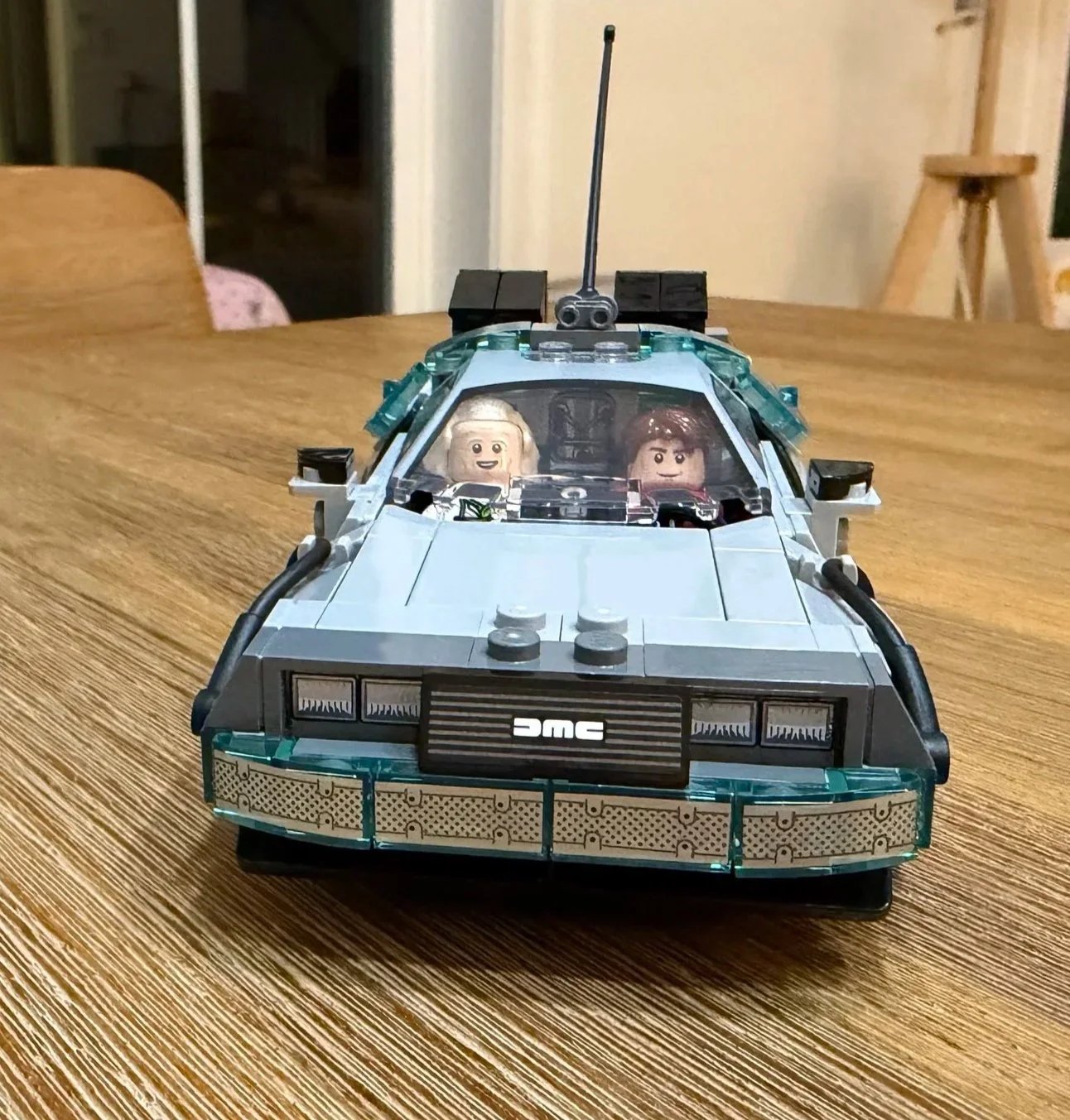 Front view of the completed LEGO DeLorean with DMC grille, black side cables, and both minifigures inside.