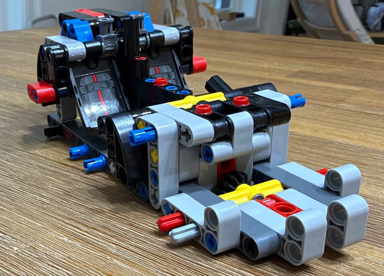 Early Ferrari FXX K chassis with two decorated black seats, gray Technic beams, and exposed blue and red connectors.