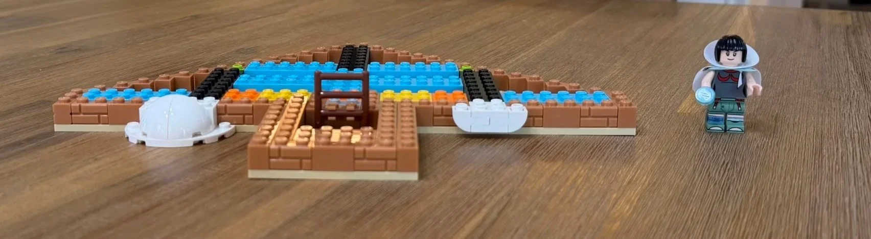 Early Rayquaza display base with exposed colored plates, a central ladder, and Zinnia beside it.
