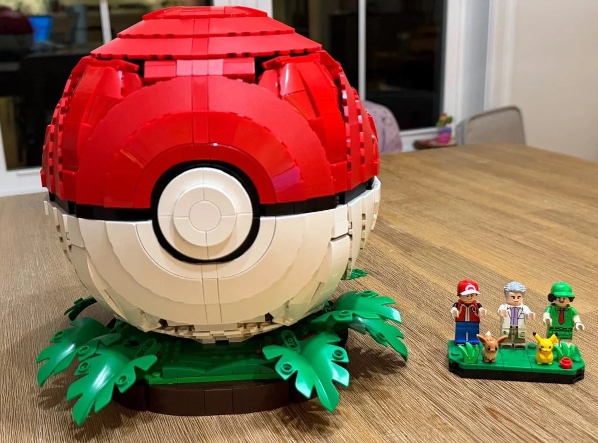 Completed red and white LEGO Pokémon Poké Ball closed on its green display base.